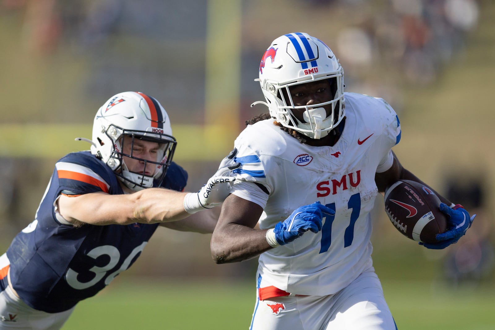 SMU running back LJ Johnson Jr. (11) defends the ball from Virginia safety Ethan Minter (30)during the second half of an NCAA college football game, Saturday, Nov. 23, 2024, in Charlottesville, Va. (AP Photo/Mike Kropf)