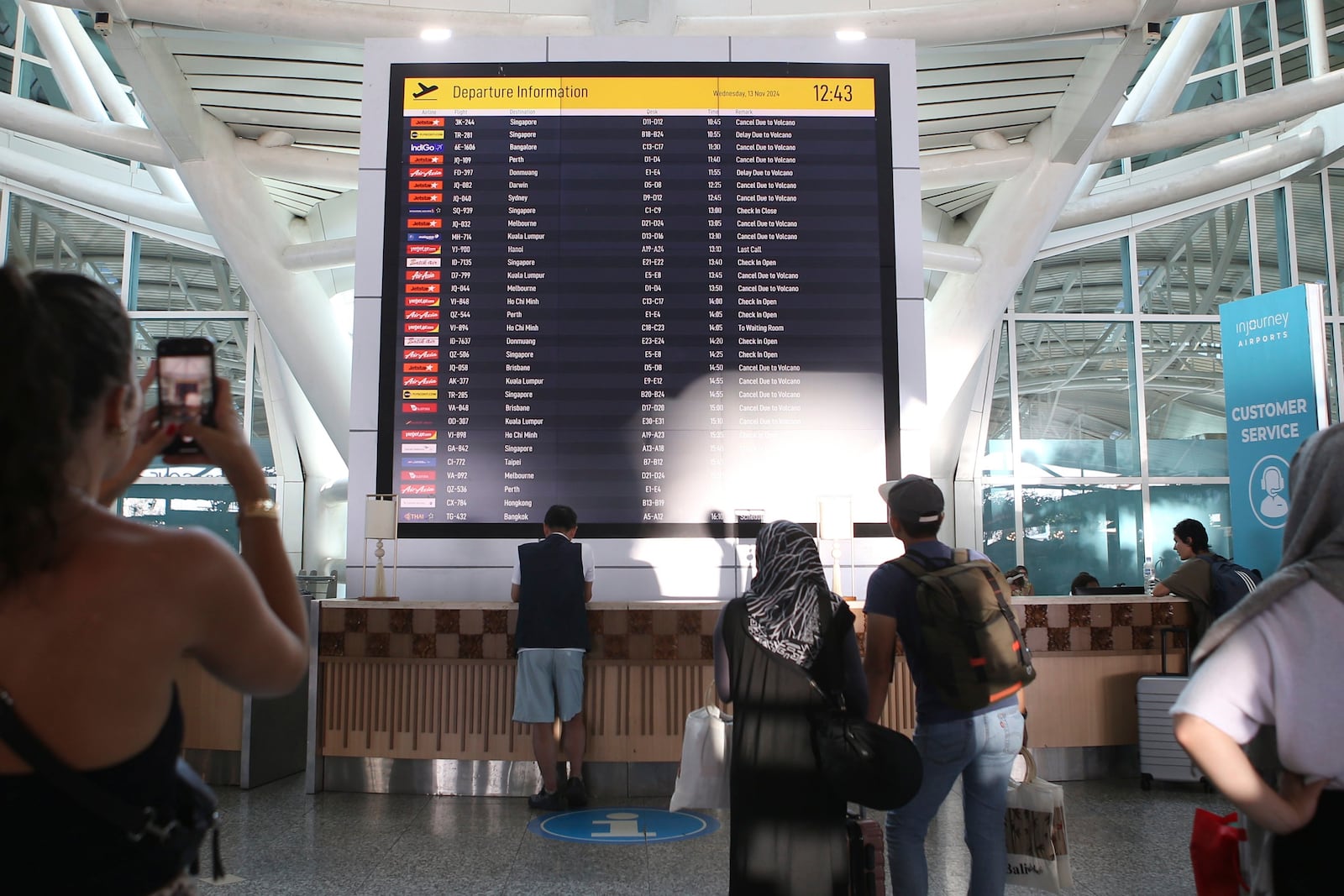 Passengers look at a flight information board showing a number of flights cancelled due to the eruption of Mount Lewotobi Laki-Laki, at Ngurah Rai International Airport in Bali, Indonesia, Wednesday, Nov. 13, 2024. (AP Photo/Firdia Lisnawati)