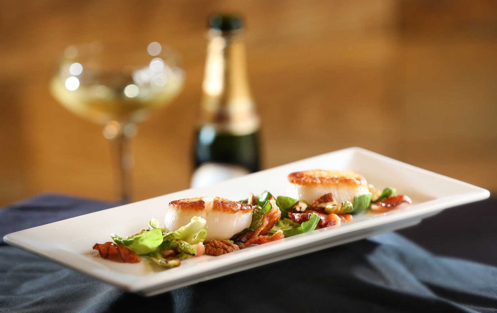 Salt-crusted scallops with brussel chips, applewood smoked bacon and pecans served with Laurent-Perrier champagne at Roost Modern Italian in the Oregon District. The restaurant was founded by chef Dana Downs who takes traditional Italian foods and uses modern techniques and ingredients to develop unique flavors. The dinner-only restaurant is located at 524 E. Fifth St. in Dayton.  LISA POWELL / STAFF