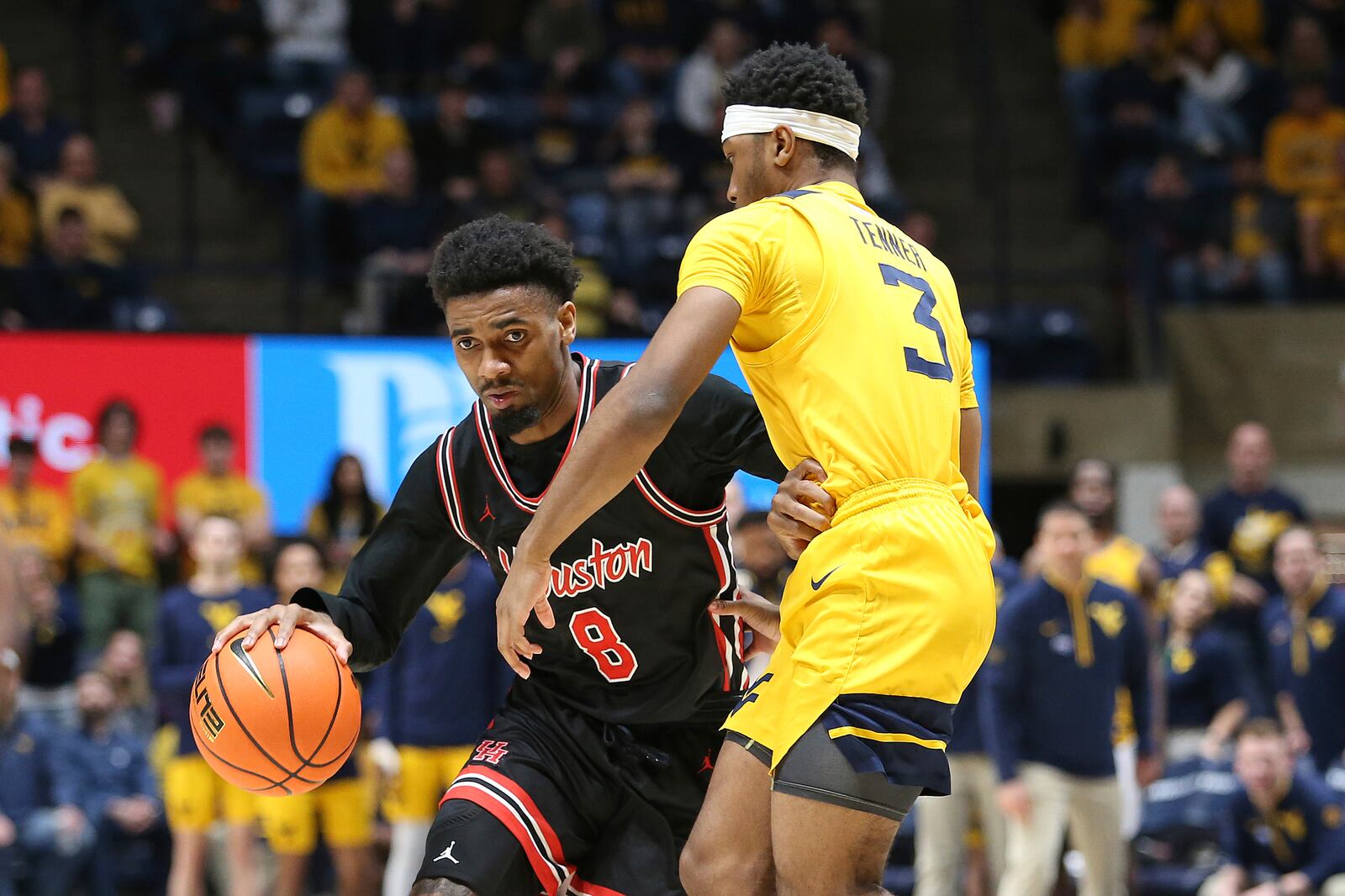 Houston guard Mylik Wilson (8) is defended by West Virginia guard KJ Tenner (3) during the second half of an NCAA college basketball game, Wednesday, Jan. 29, 2025, in Morgantown, W.Va. (AP Photo/Kathleen Batten)