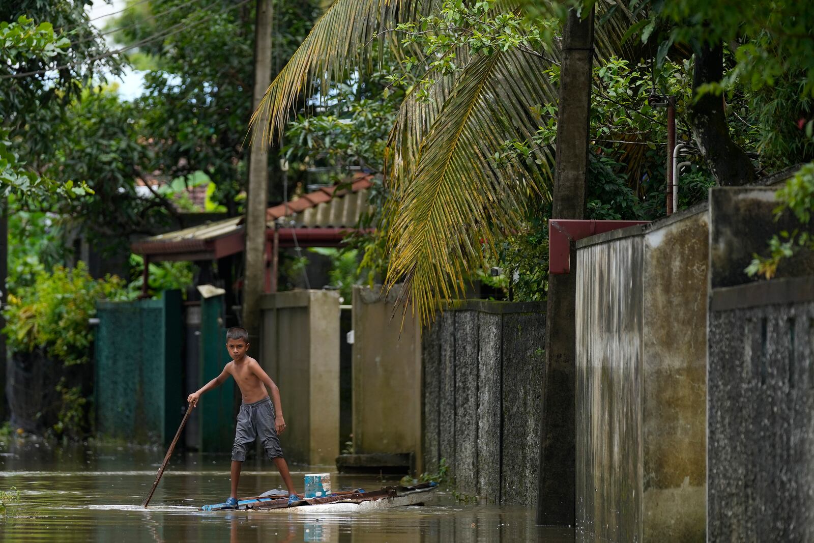 A boy plays with a makeshift raft at a flooded neighborhood in Colombo, Sri Lanka, Monday, Oct. 14, 2024. (AP Photo/Eranga Jayawardena)