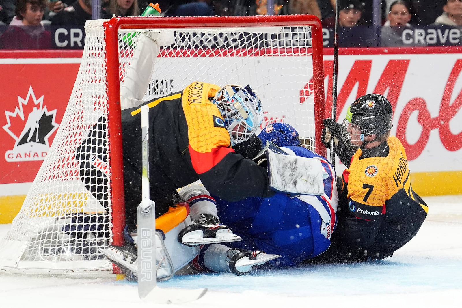 USA forward Danny Nelson (17) and Germany defenceman Carlos Handel (7) crash into Nico Pertuch's (1) net during first period IIHF World Junior Hockey Championship preliminary round action in Ottawa on Thursday, Dec. 26, 2024. (Sean Kilpatrick/The Canadian Press via AP)