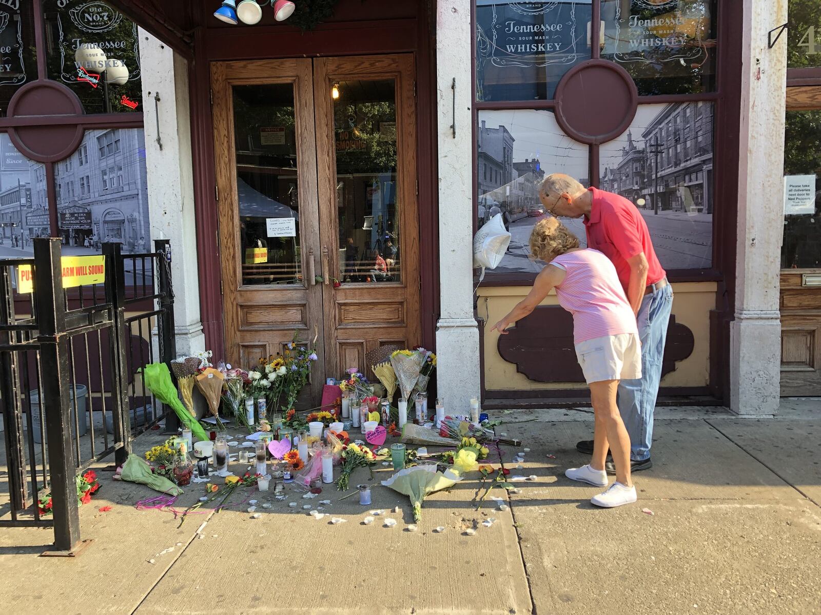 Mary Jo and Bill Koachmar place a candle in front of the memorial outside of Ned Pepper’s Bar. BONNIE MEIBERS/STAFF