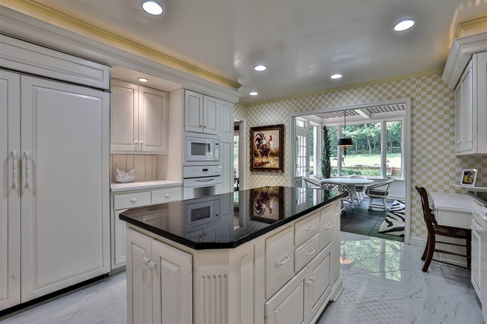 In the kitchen, dark counters complement the white cabinetry, which includes an island with open cookbook shelves. Contributed