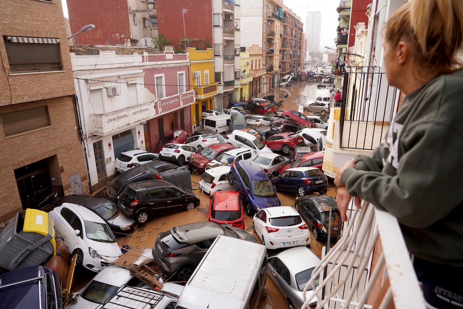 A woman looks out from her balcony as vehicles are trapped in the street after flooding in Valencia, Wednesday, Oct. 30, 2024. (AP Photo/Alberto Saiz)