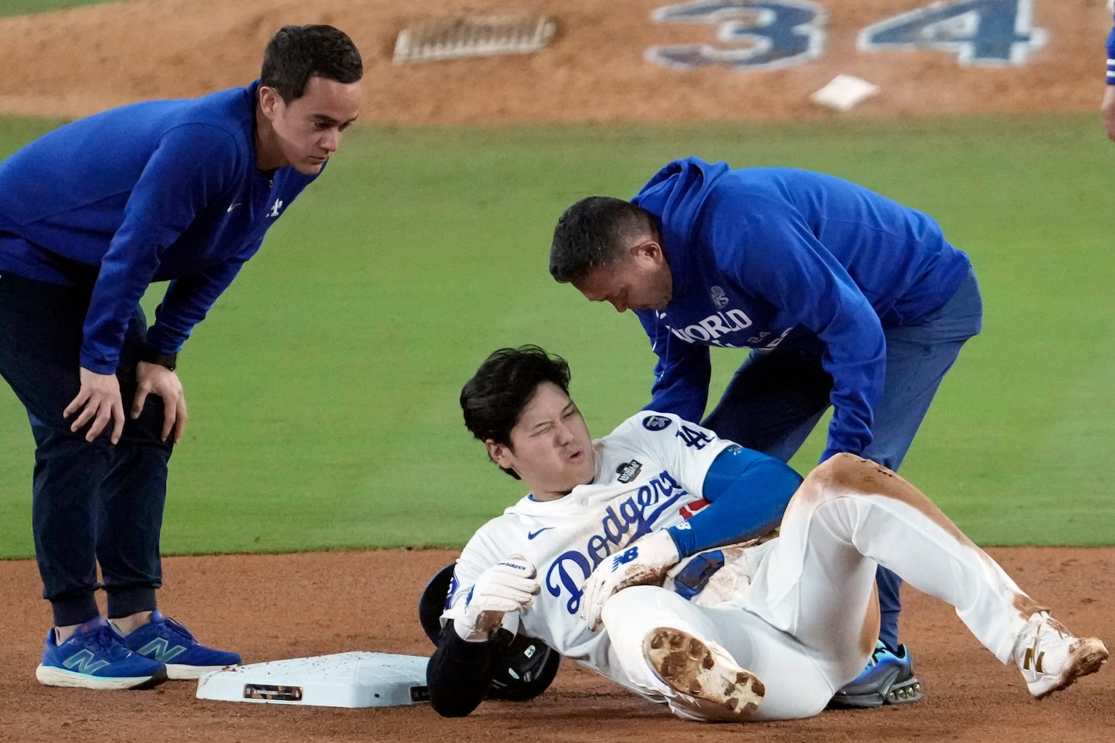 Los Angeles Dodgers' Shohei Ohtani, center, reacts after being injured while trying to steal second base against the New York Yankees during the seventh inning in Game 2 of the baseball World Series, Saturday, Oct. 26, 2024, in Los Angeles. (AP Photo/Julio Cortez)