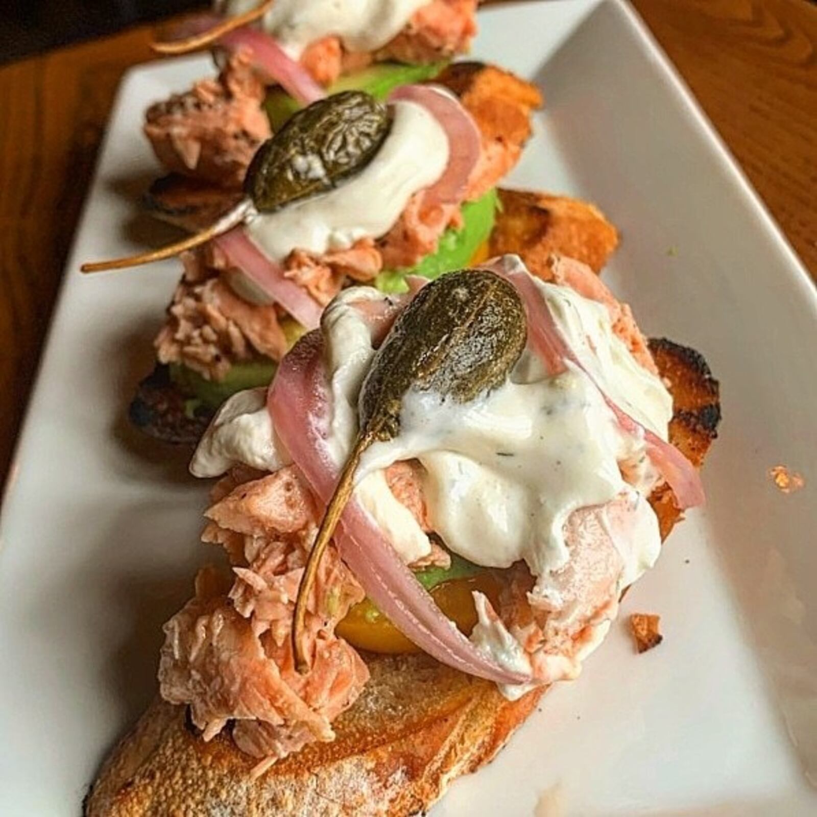 The salmon avo toast has sliced avocado, pickled onion, fresh dill crema, fried capers and yellow tomato. CONTRIBUTED