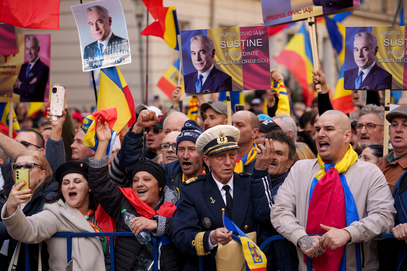 Supporters of Calin Georgescu, the winner of the first round of presidential elections, later annulled by the Constitutional Court, shout slogans after gathering to see him register a new bid for the country's presidency outside Romania's Electoral Authority, in Bucharest, Romania, Friday, March 7, 2025. (AP Photo/Vadim Ghirda)