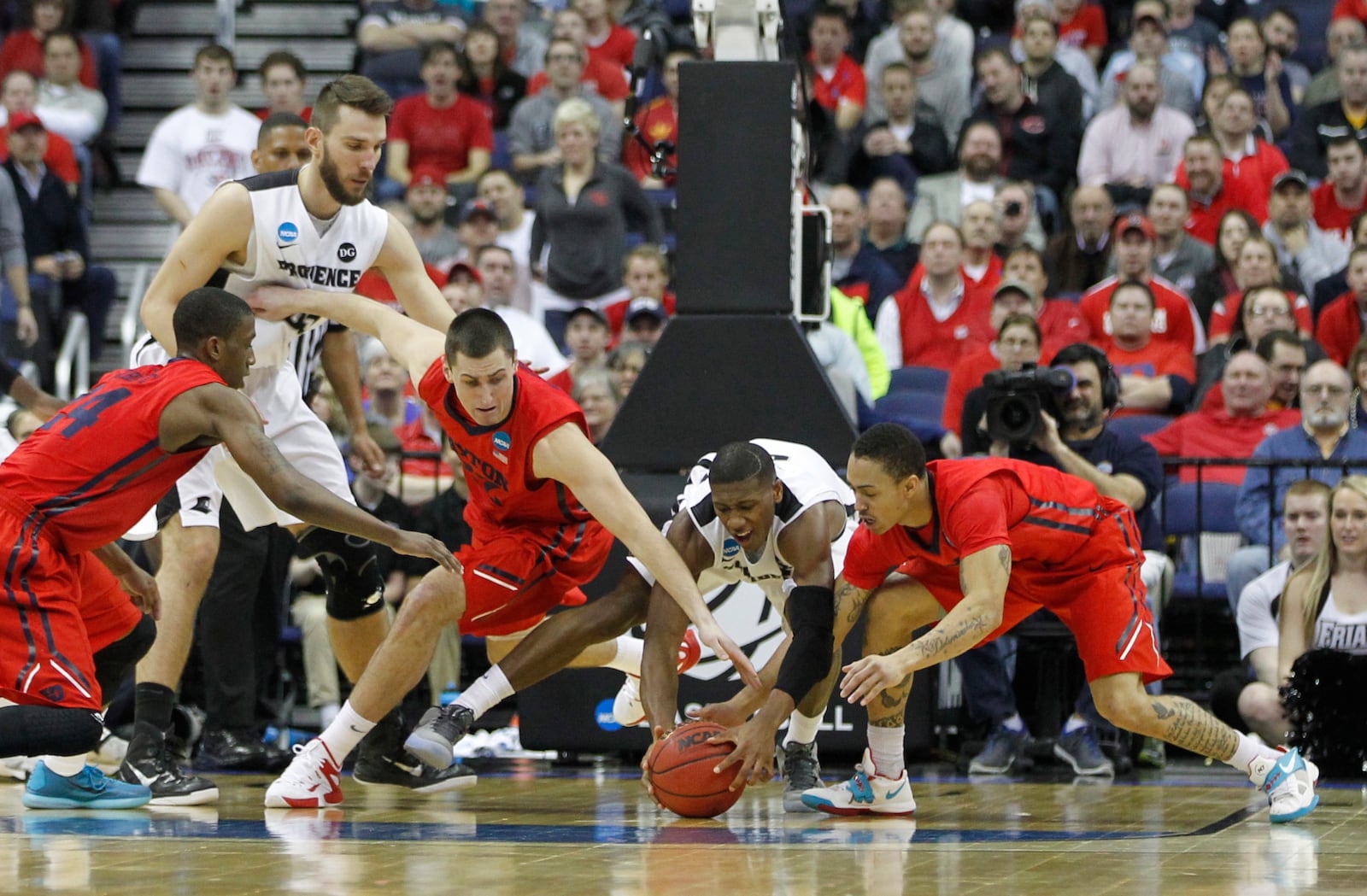 Dayton's Jordan Sibert, left, Bobby Wehrli, center, and Kyle Davis, right, dive for a loose ball against Providence's Kris Dunn in the second round of the NCAA tournament on Friday, March 20, 2015, at Nationwide Arena in Columbus. David Jablonski/Staff