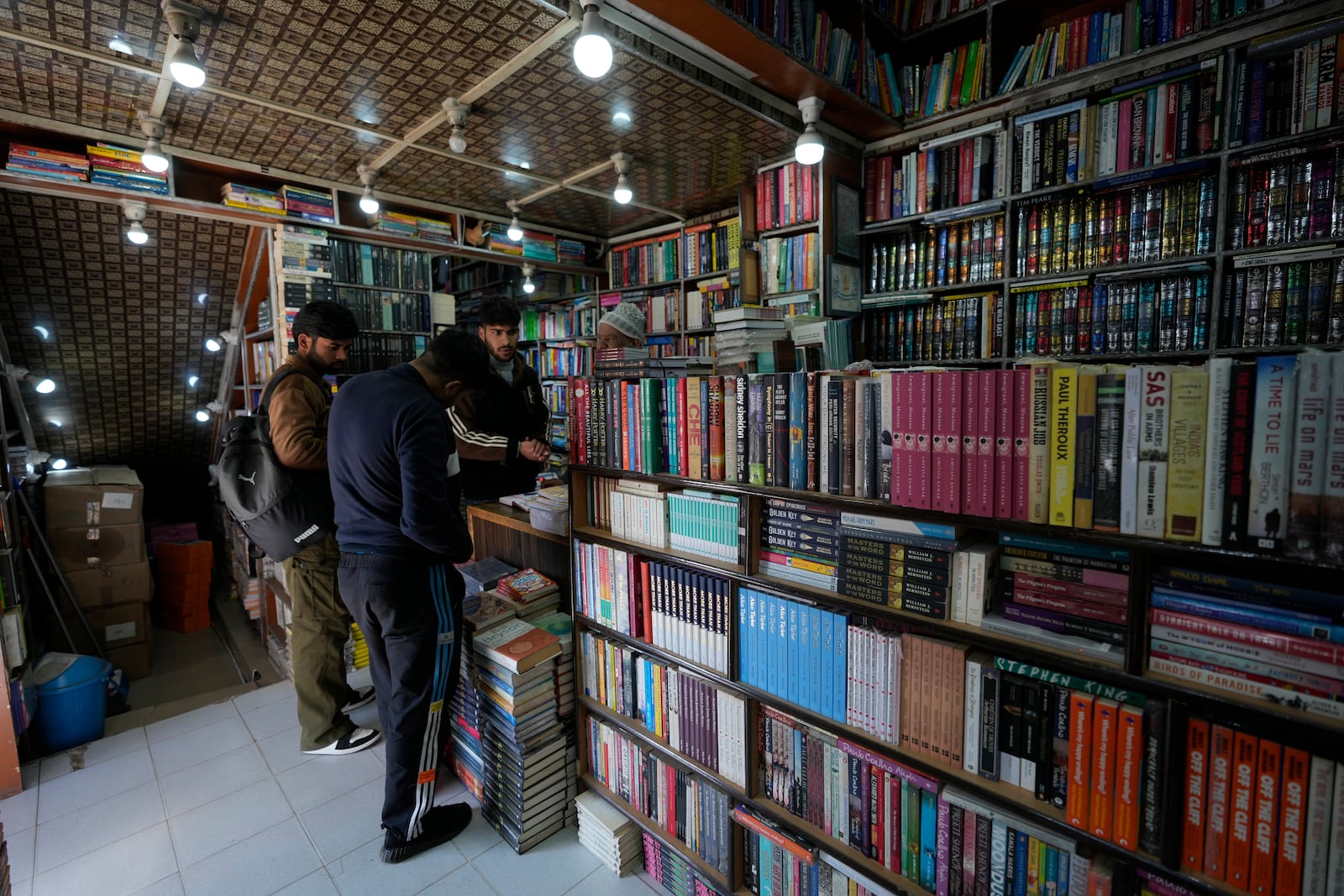 Kashmiri men purchase books at a book shop in Srinagar, Indian controlled Kashmir, Monday, Feb. 17, 2025. (AP Photo/Mukhtar Khan)