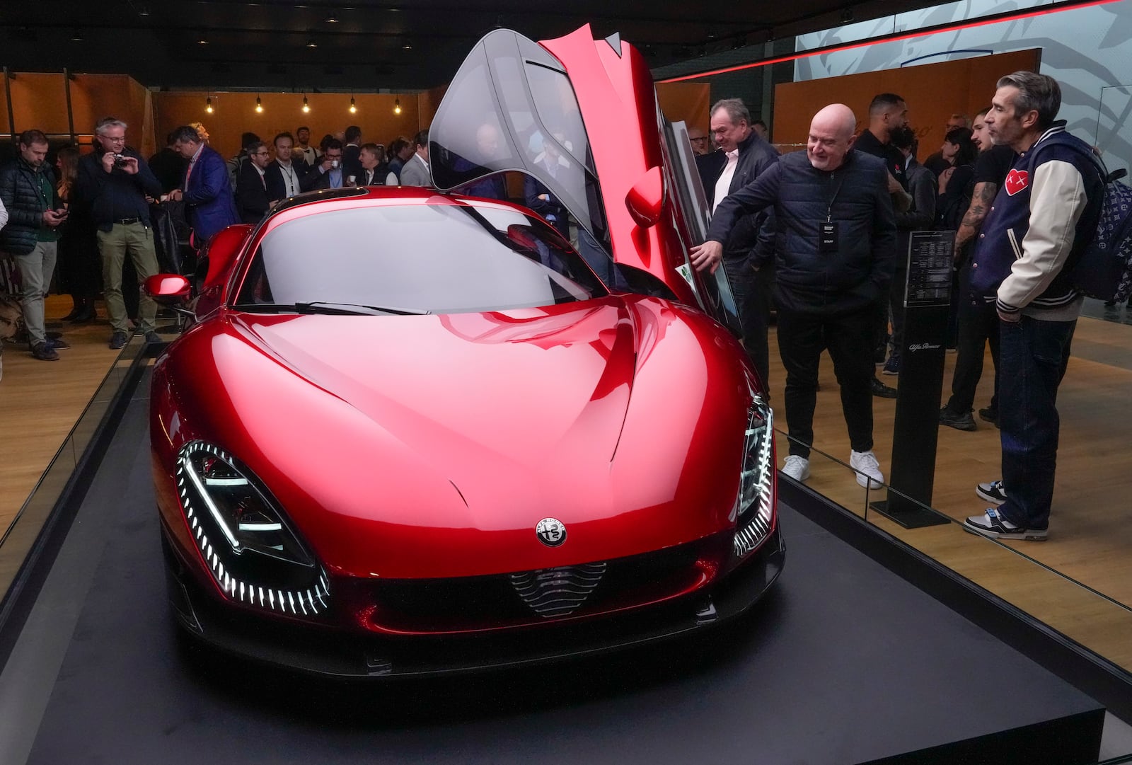 People looks at the Alfa Romeo 33 Stradale car at the Paris Auto Show, in Paris, Monday, Oct. 14, 2024. (AP Photo/Michel Euler)