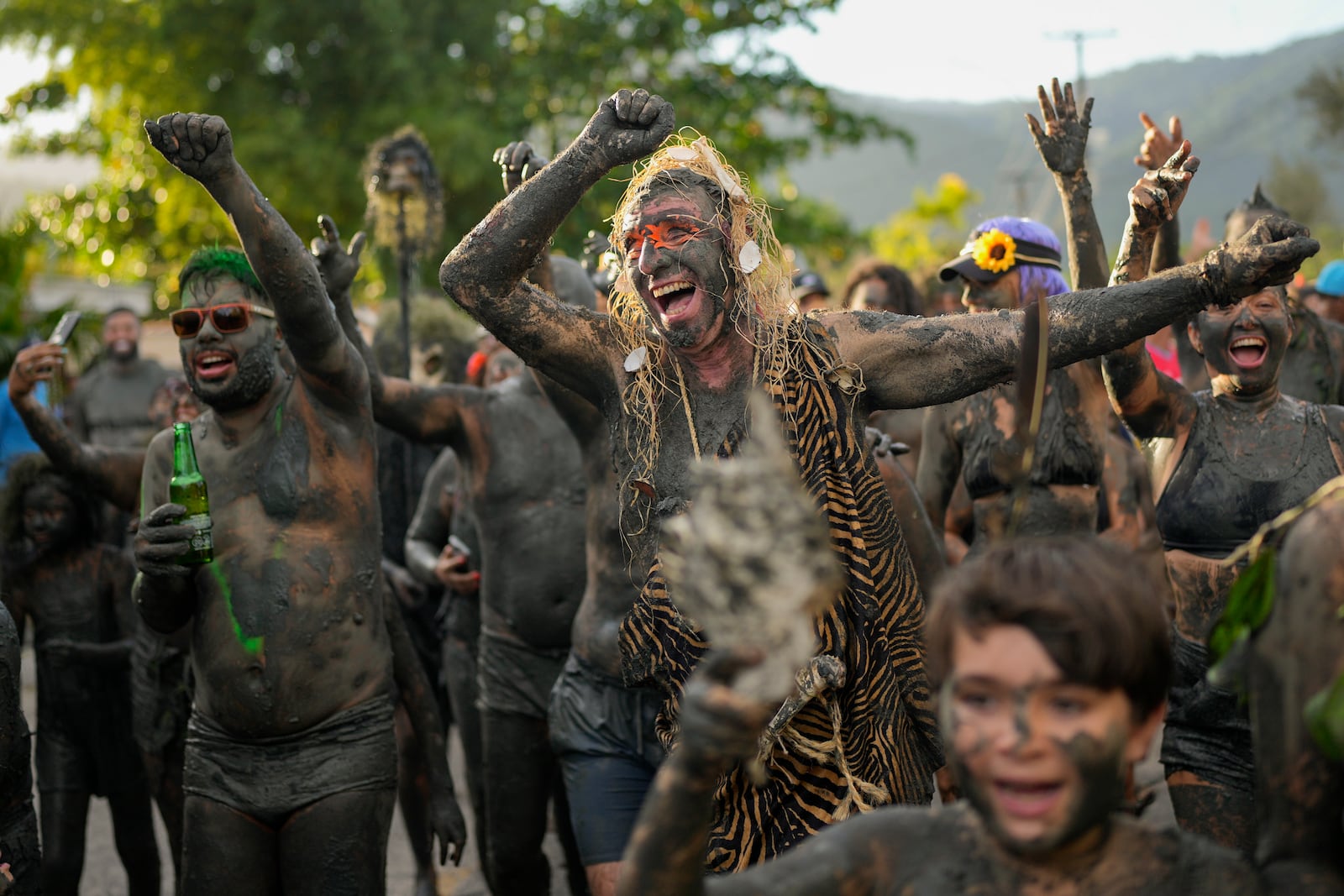 Revelers cheer during the Mud Block carnival party in Paraty, Brazil, Saturday, March 1, 2025. (AP Photo/Andre Penner)