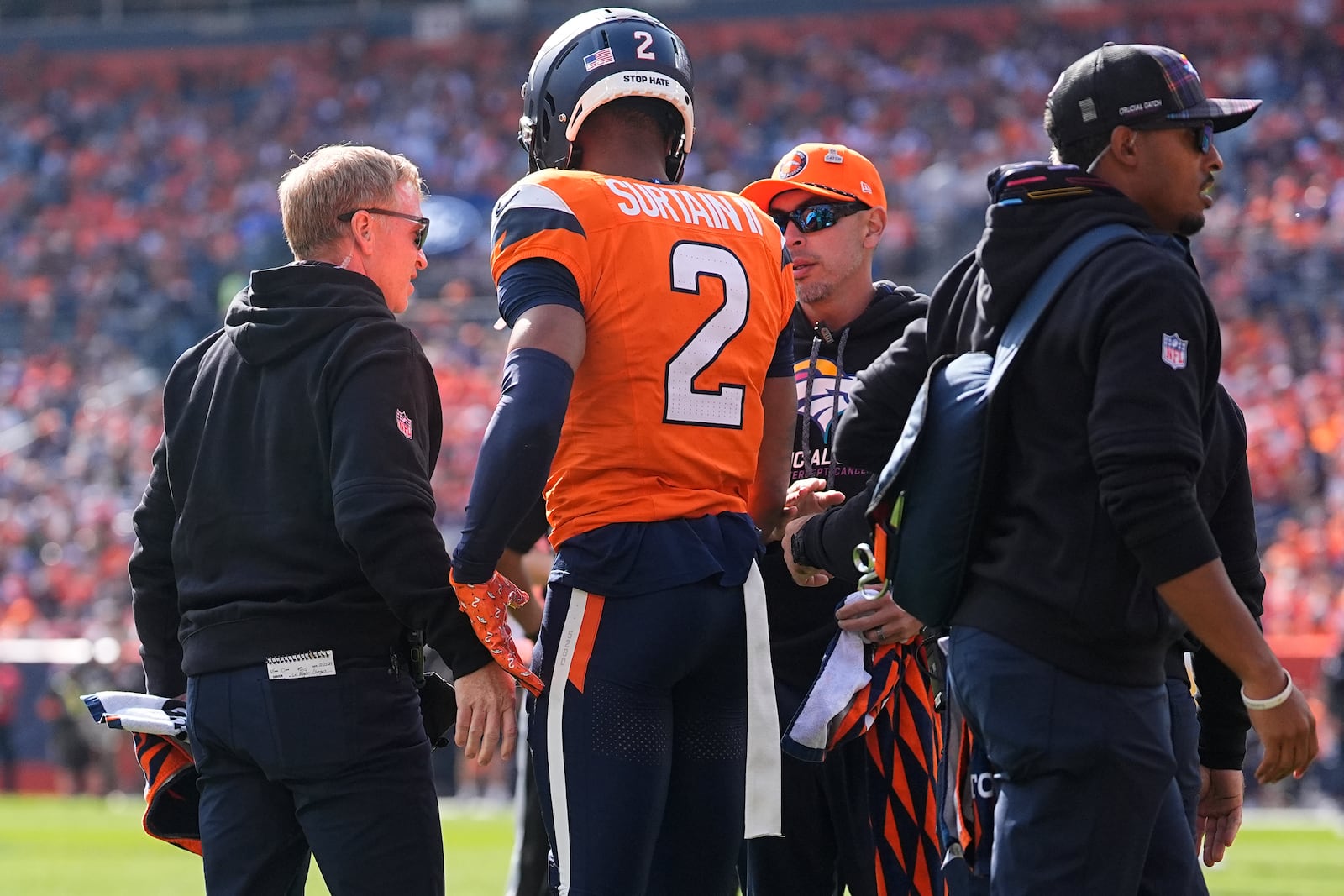 Denver Broncos cornerback Pat Surtain II (2) stands with trainers after sustaining an injury during the first half of an NFL football game against the Los Angeles Chargers, Sunday, Oct. 13, 2024, in Denver. (AP Photo/David Zalubowski)