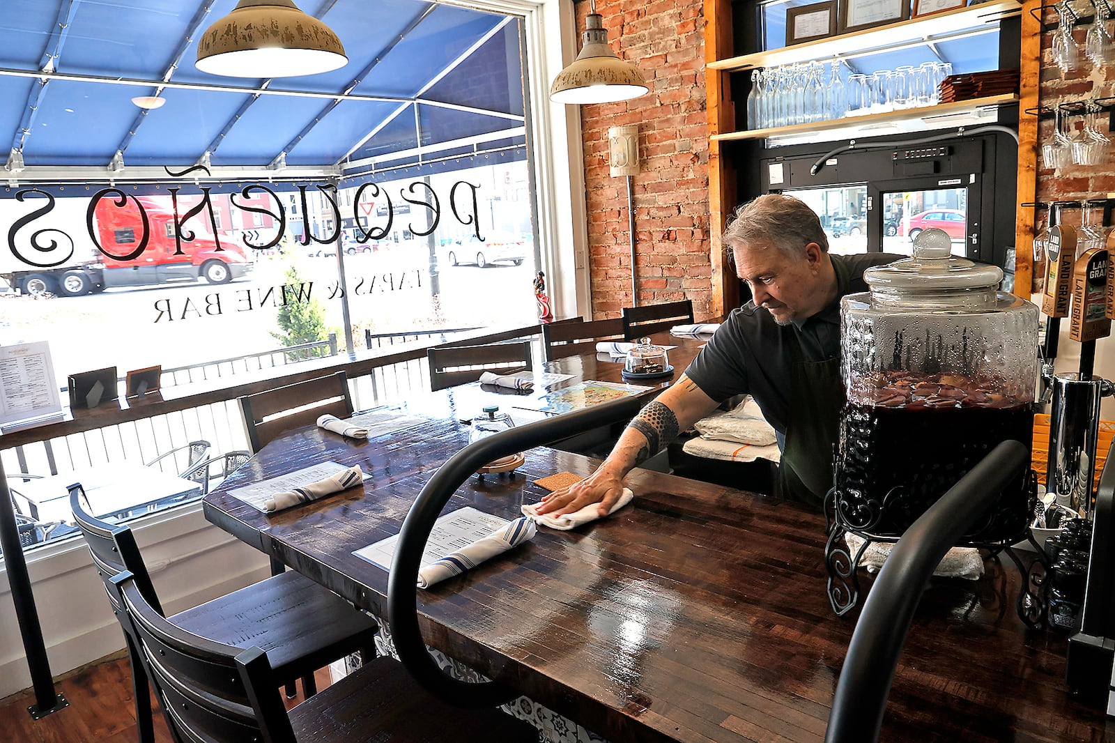 Jonathan Kouse, one of the three owners of Pequeños Tapas and Wine Bar in Urbana, gets ready for the ribbon cutting and grand opening Wednesday, April 19, 2023. BILL LACKEY/STAFF