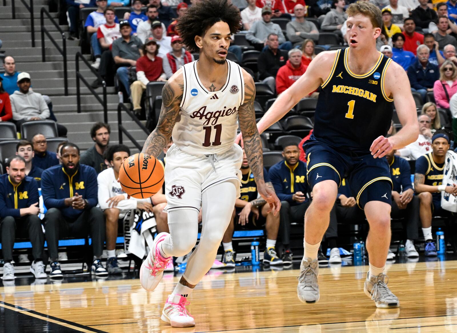 Texas A&M forward Andersson Garcia, left, drives past Michigan center Danny Wolf, right, during the first half in the second round of the NCAA college basketball tournament Saturday, March 22, 2025, in Denver. (AP Photo/John Leyba)