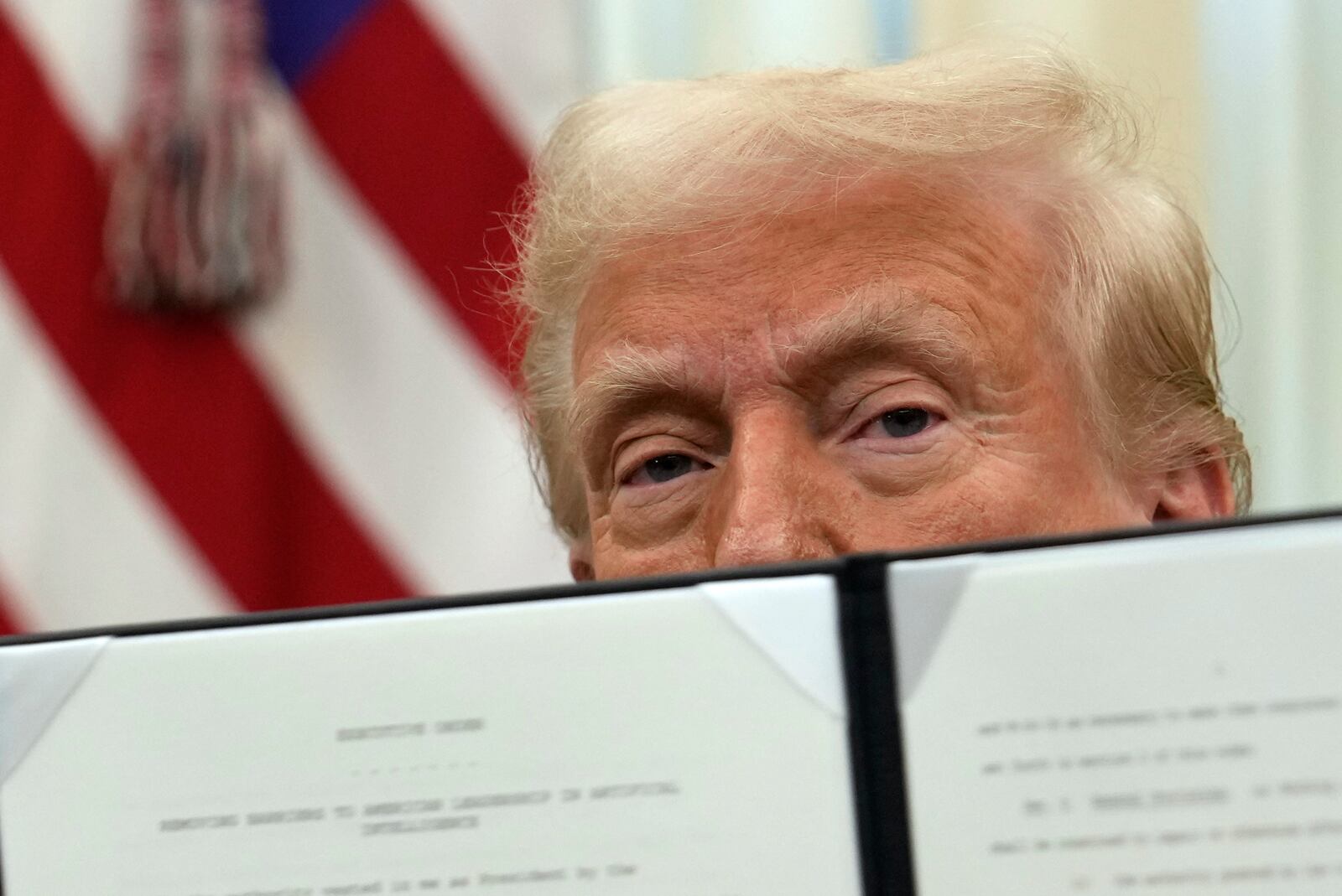 President Donald Trump holds up a signed executive order regarding cryptocurrency in the Oval Office of the White House, Thursday, Jan. 23, 2025, in Washington. (AP Photo/Ben Curtis)