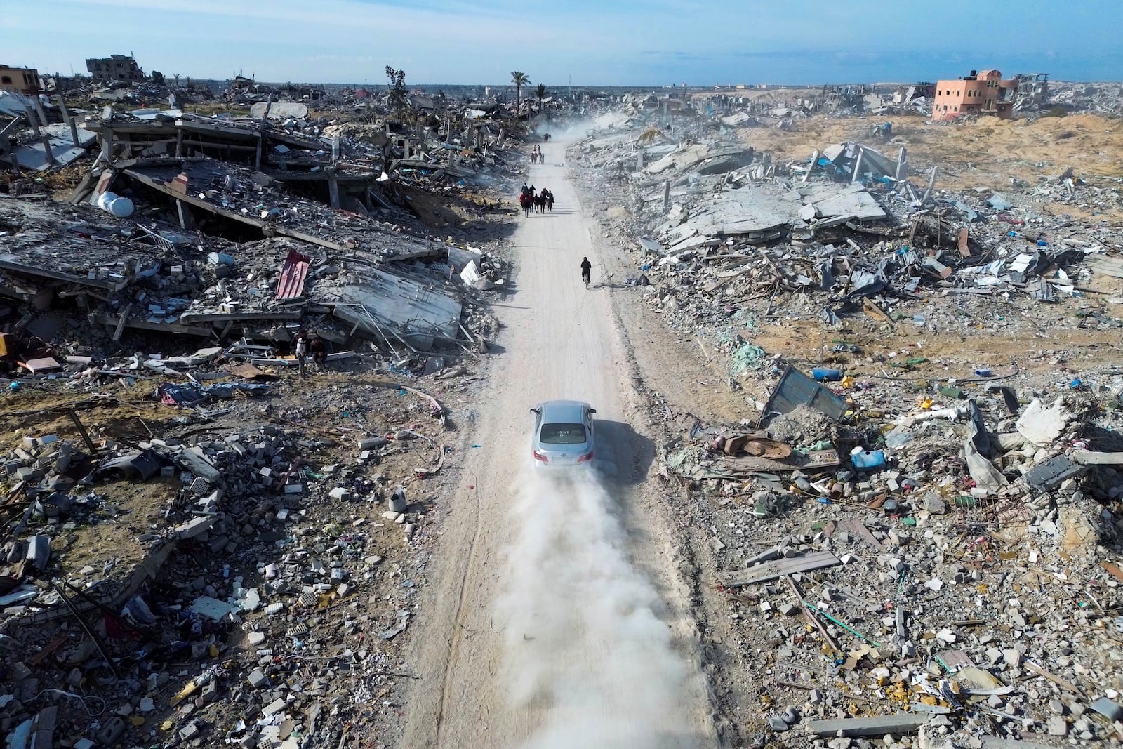 Palestinians walk through the destruction by the Israeli air and ground offensive in Rafah, as a ceasefire deal between Israel and Hamas went into effect Sunday, Jan. 19, 2025. (AP Photo/Jehad Alshrafi)