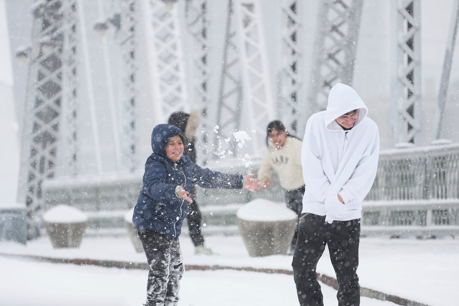 Joselyn Catlan, 9, left, tosses snow on Daniel Ruiz in the snow Friday, Jan 10, 2025, in Nashville, Tenn. (AP Photo/George Walker IV)