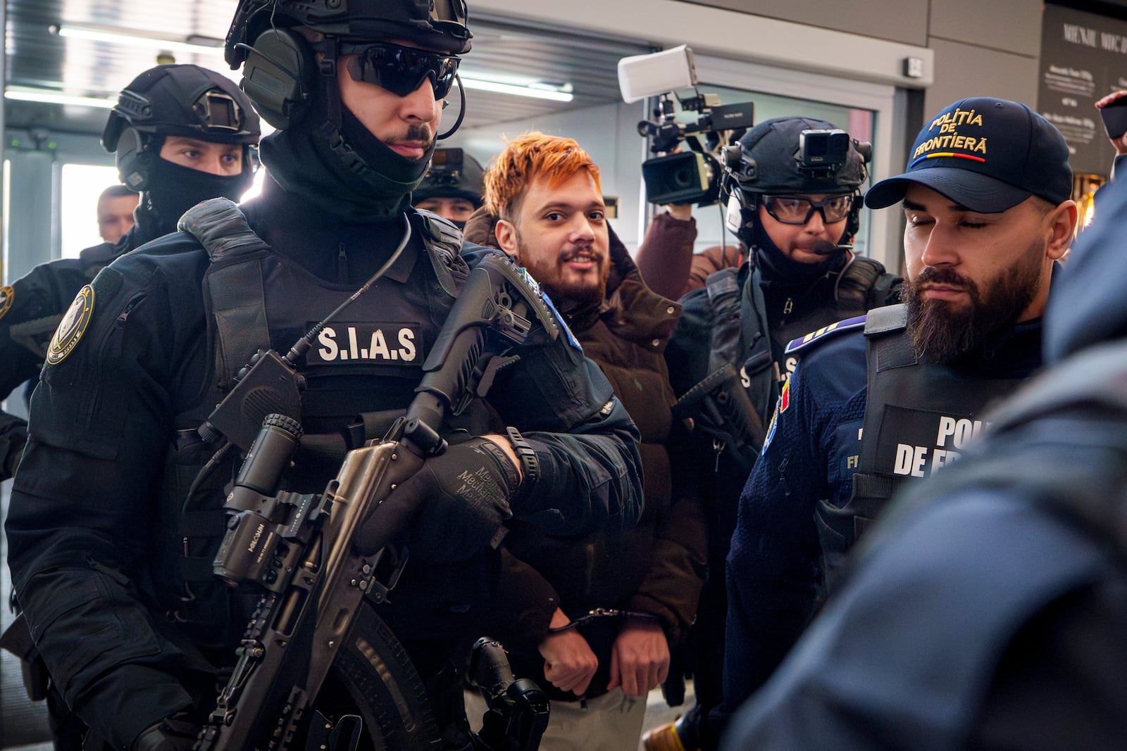 Mohamed Amra, nicknamed ''The Fly", is escorted by armed police officers at the Henri Coanda international airport in Otopeni, Romania, Tuesday, Feb. 25, 2025, before being extradited to France. (AP Photo/Vadim Ghirda)