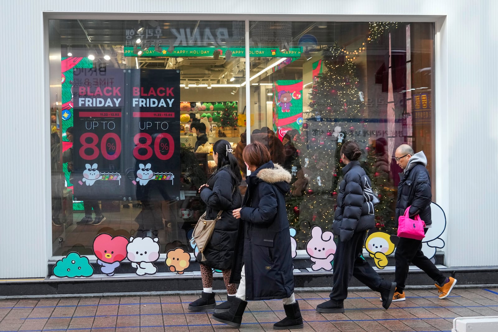 People walk by sale signs on the shopping street in Seoul, South Korea, Thursday, Nov. 28, 2024.(AP Photo/Ahn Young-joon)