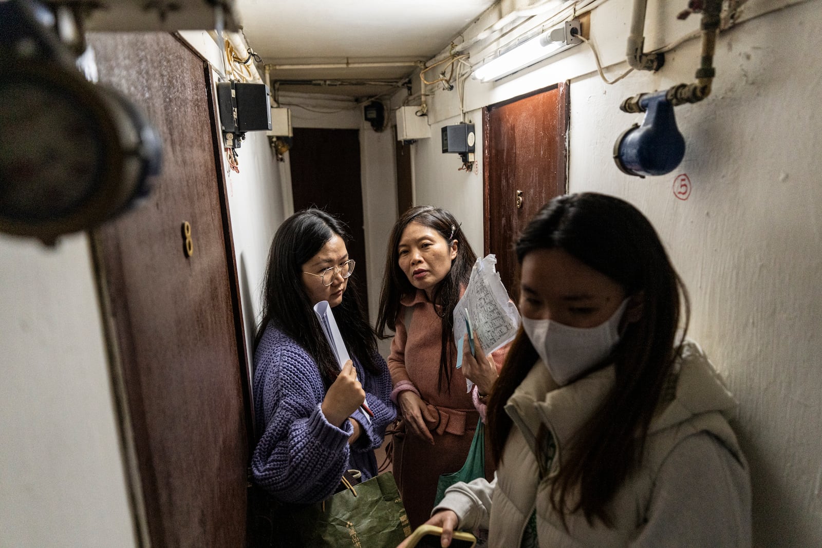 Sze Lai-shan, the deputy director of the Society for Community Organization, center, and her colleagues visit residents in the subdivided flat in Sham Shui Po district of Hong Kong, on Feb. 6, 2025. (AP Photo/Chan Long Hei)