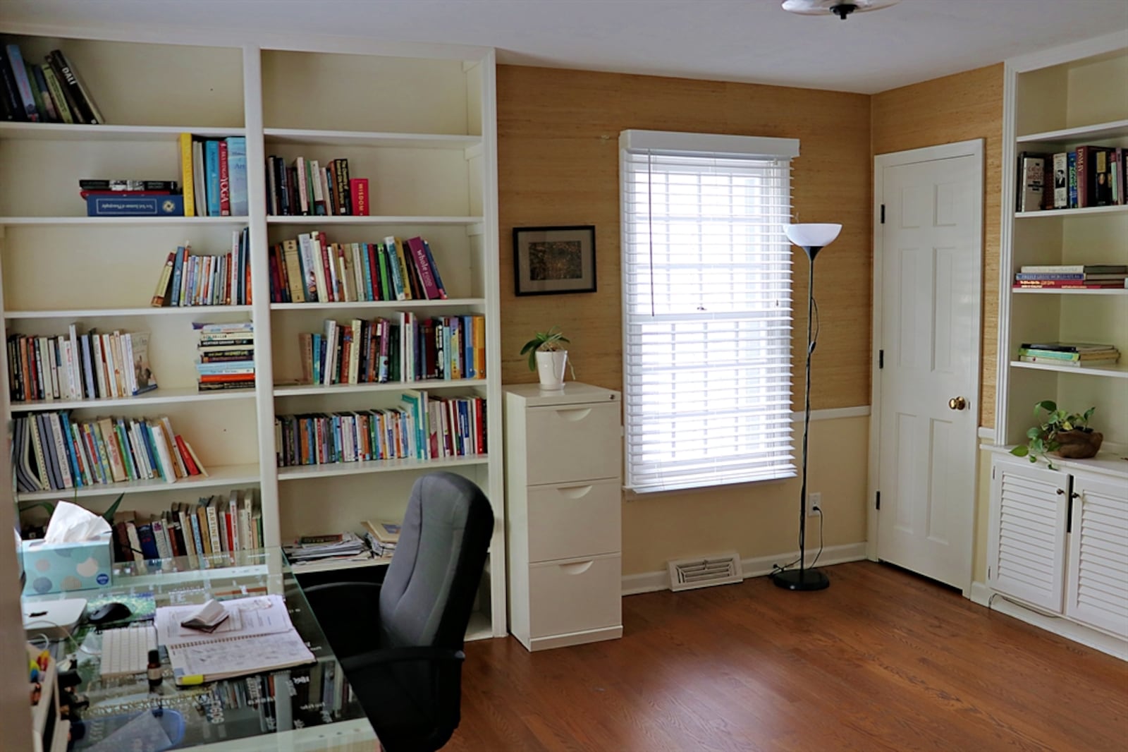 The study has three large windows, walls of built-in bookcases and cabinetry and a closet. 