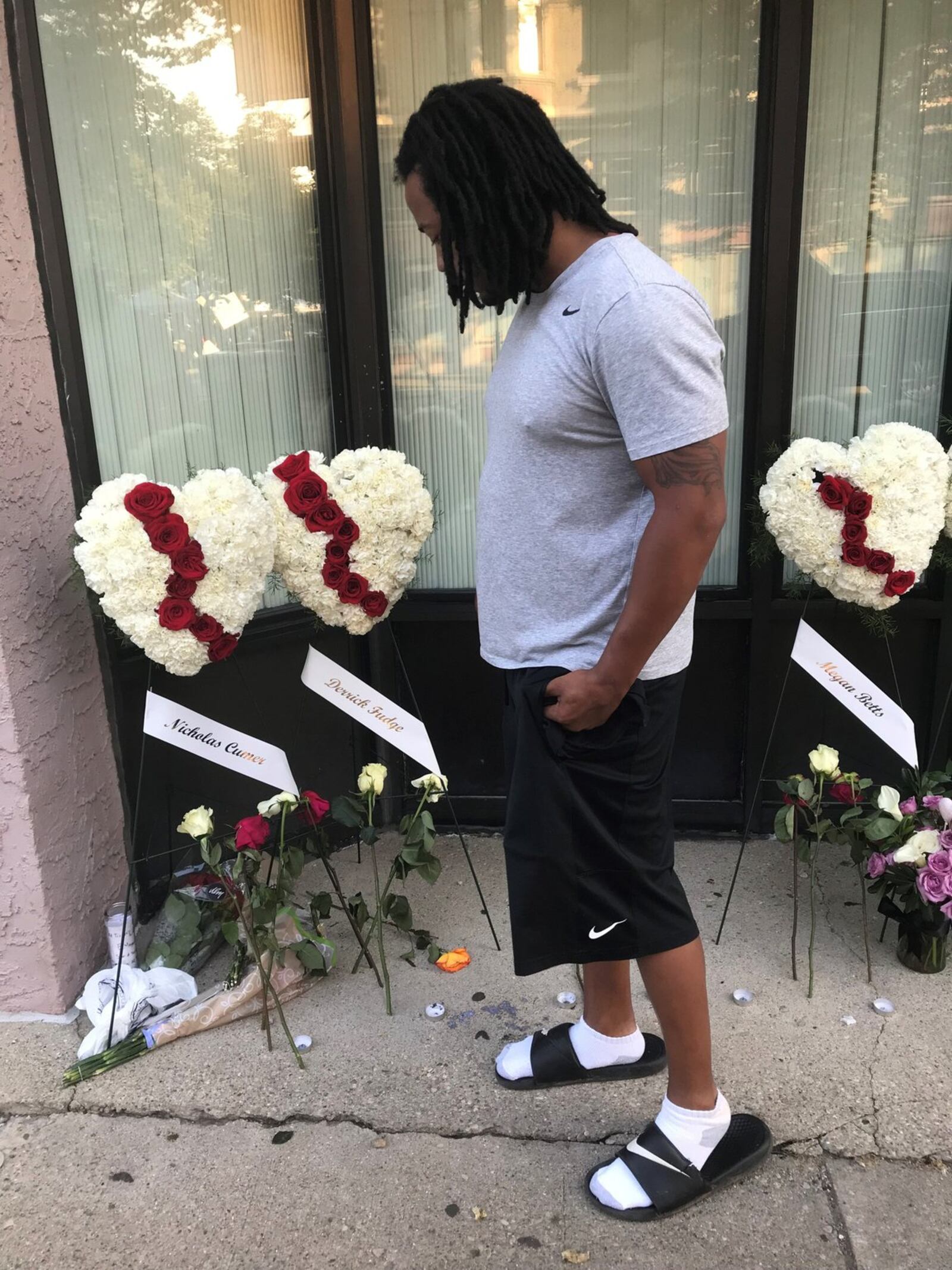 Dion Green looks at a memorial set up in Dayton’s Oregon District to honor the nine victims of the Dayton mass shooting, including his father Derrick Fudge of Springfield. STAFF