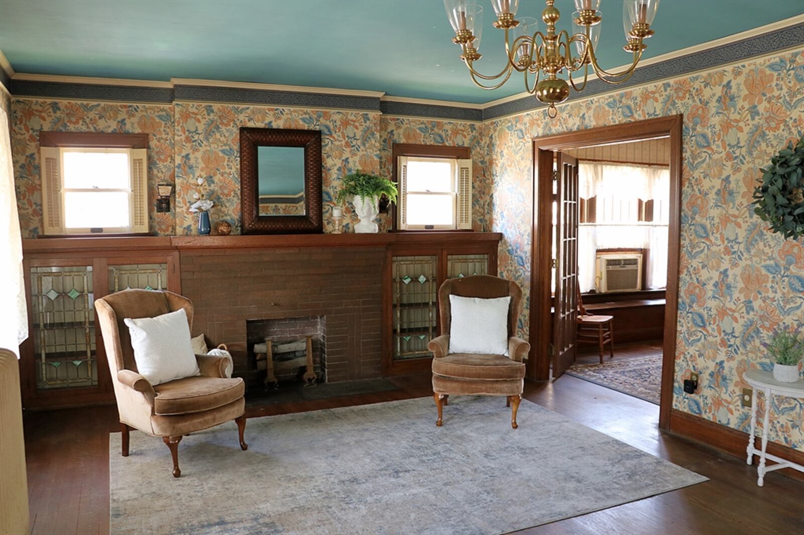 In the living room, a decorative brick fireplace is flanked by built-in cabinets with stained-glass panel doors. 