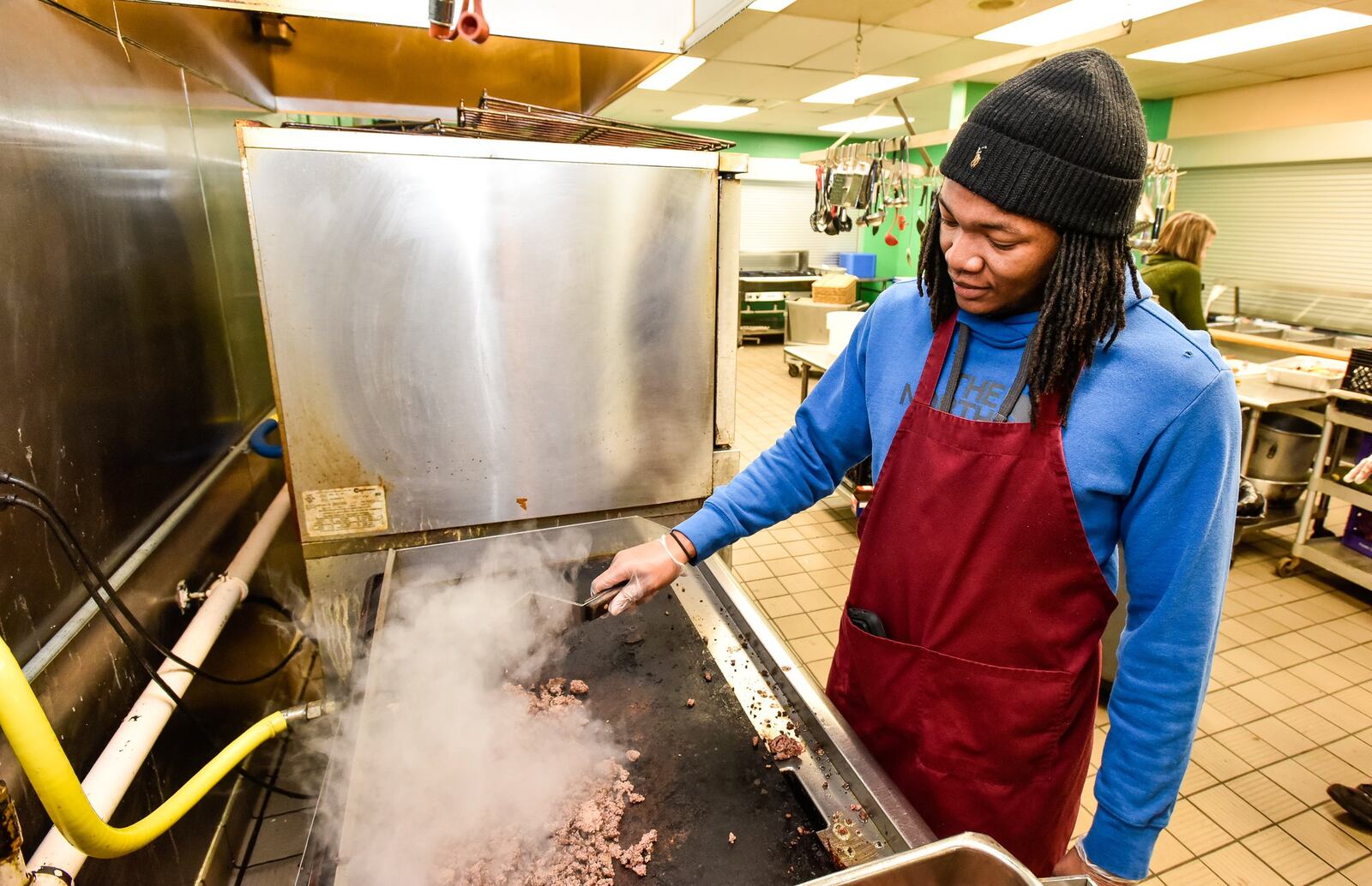 Volunteer Preston Yeldell, Jr. cooks meet on the grill at House of Bread non-profit community kitchen Friday, Dec. 20, 2019 in Dayton. Yeldell is volunteering while he is home from Ohio Dominican University for the holiday break. NICK GRAHAM/STAFF