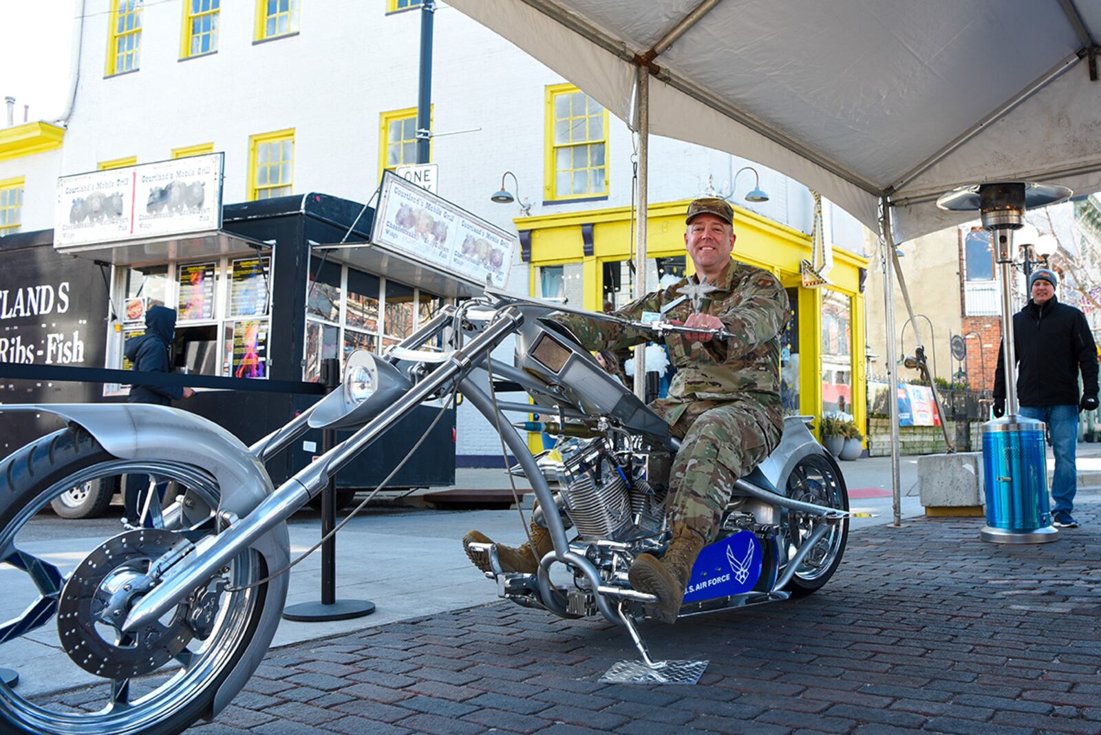 Col. Patrick Miller, 88th Air Base Wing commander, tries out the Orange County Chopper from the National Museum of the U.S. Air Force at Family Fest in the Oregon District on March 13. Since 2012, the Big Hoopla has showcased Dayton’s collaborative spirit, community support and military appreciation as host of the NCAA men's basketball tournament First Four. U.S. AIR FORCE PHOTO/SENIOR AIRMAN ALEXANDRIA FULTON