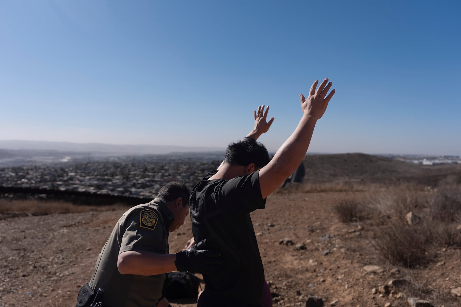 Border Patrol Agent Gutierrez pats down one of four men after the group crossed the border illegally through a gap in two walls separating Mexico from the United States before turning themselves in, Thursday, Jan. 23, 2025, in San Diego. (AP Photo/Gregory Bull)