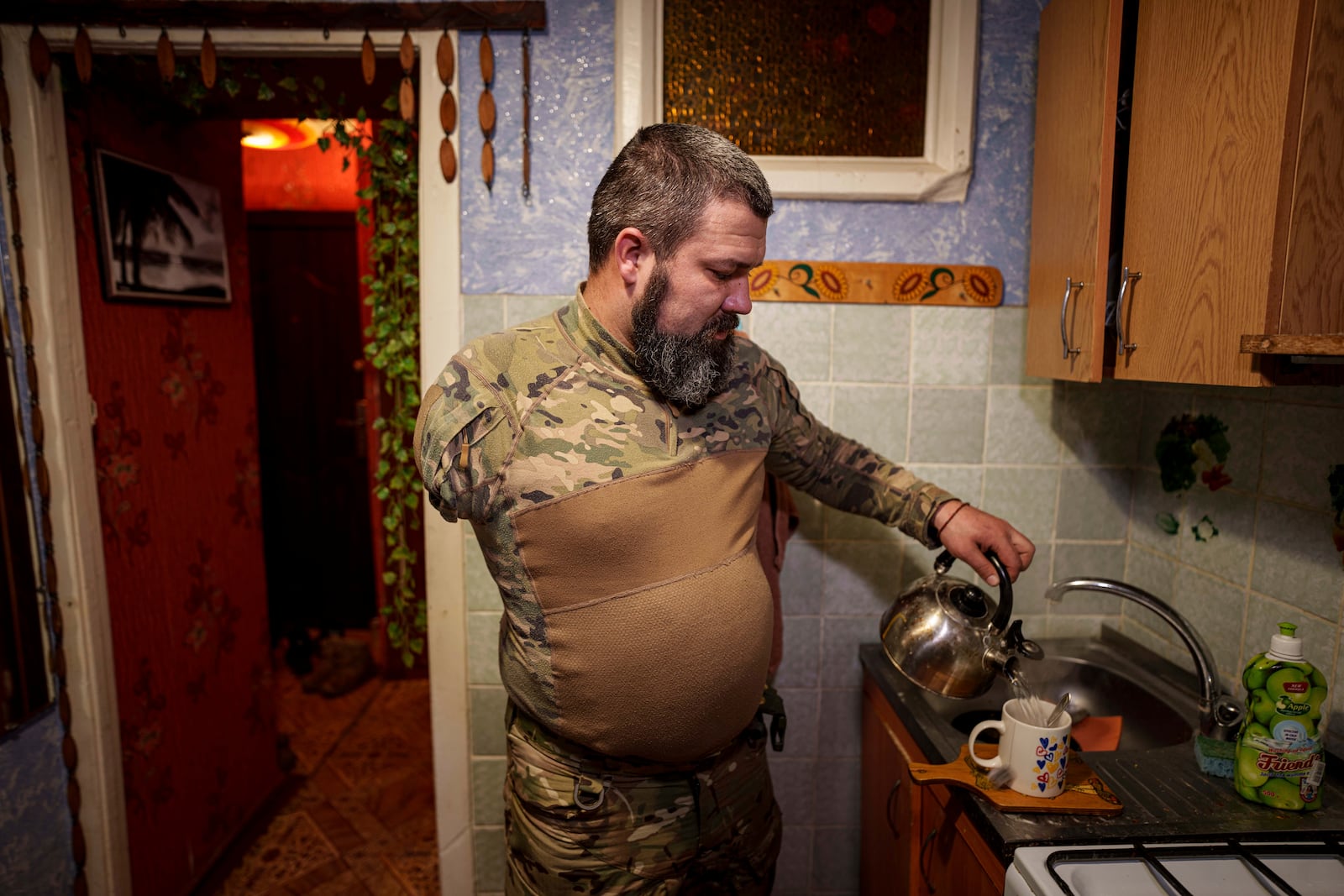 Ukrainian soldier Oleksandr Zhalinskyi of the Azov brigade, who lost his right arm in battle, makes tea at his apartment in Ukraine's Donetsk region on Jan. 31, 2025. (AP Photo/Evgeniy Maloletka)