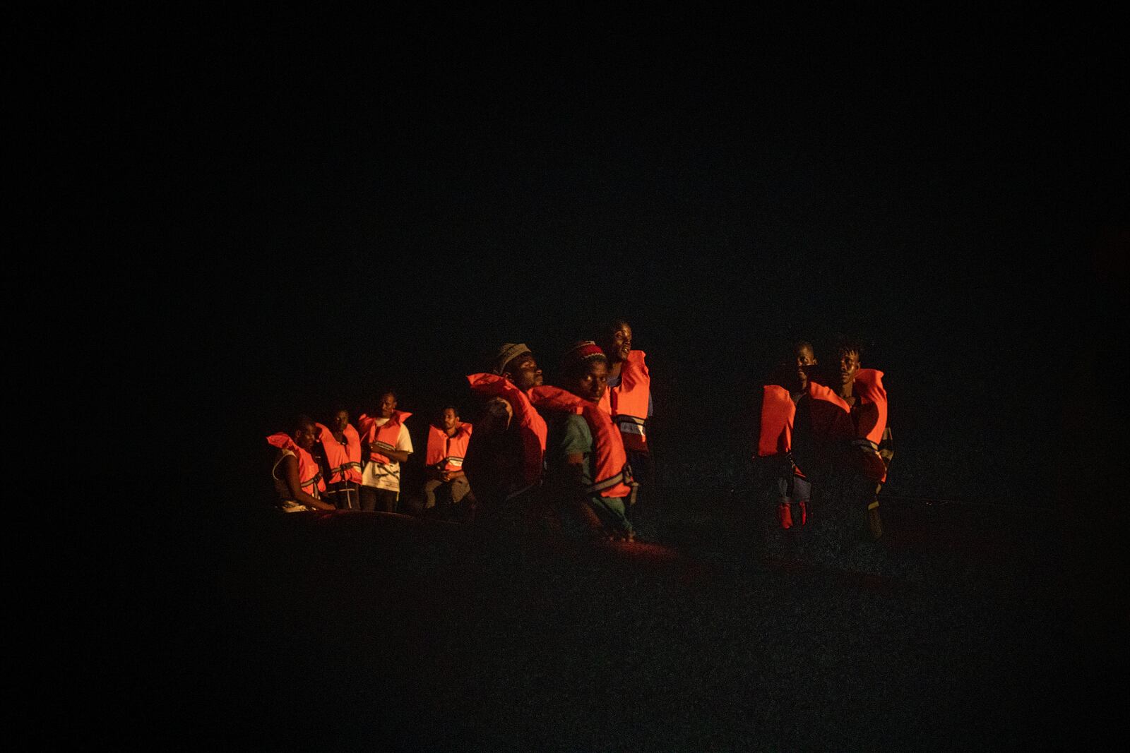 Men from different African nationalities wait to be assisted by crew members of the Louise Michel and Astral rescue vessels, after being located sailing adrift on an overcrowded rubber boat, 70 miles southwest Malta, in the Central Mediterranean sea, Saturday, Aug. 29, 2020. A rescue ship painted and sponsored by British artist Banksy saved another 130 migrants stranded on a rubber boat in the Southern Mediterranean Sea. (AP Photo/Santi Palacios)