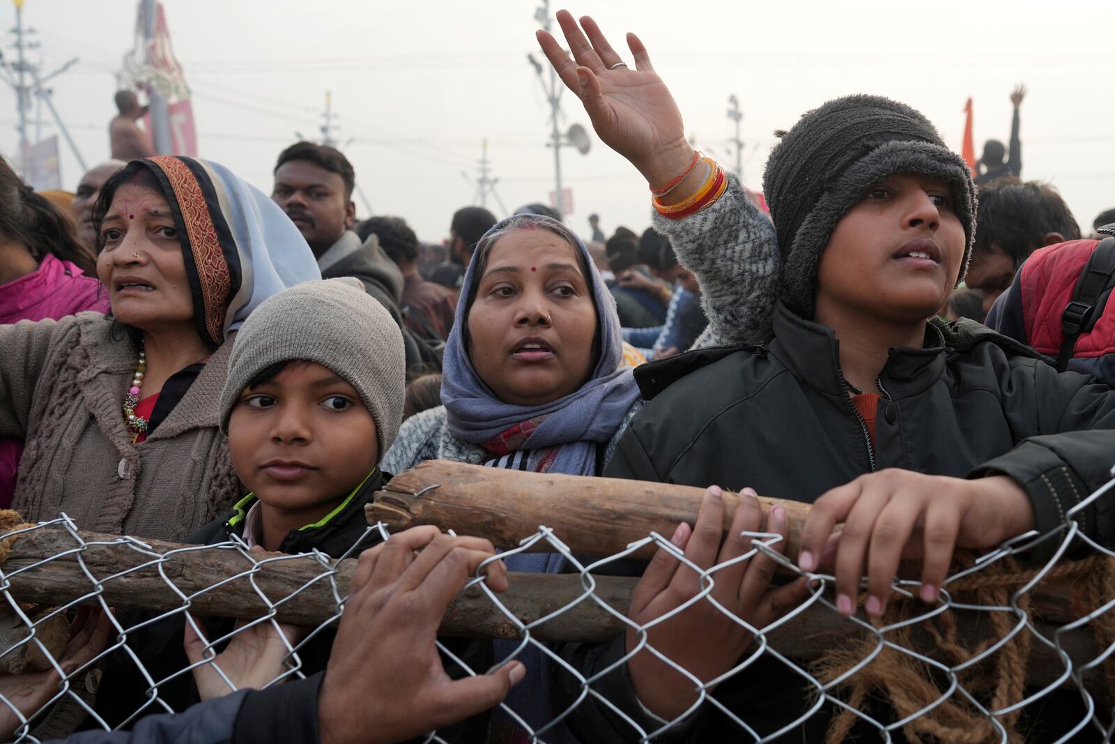 Hindu devotees stand behind a barricade and wait to take a holy dip in the Sangam, the confluence of the Ganges, the Yamuna and the mythical Saraswati rivers, on "Mauni Amavasya" or new moon day during the Maha Kumbh festival in Prayagraj, India, Wednesday, Jan. 29, 2025. (AP Photo/Rajesh Kumar Singh)