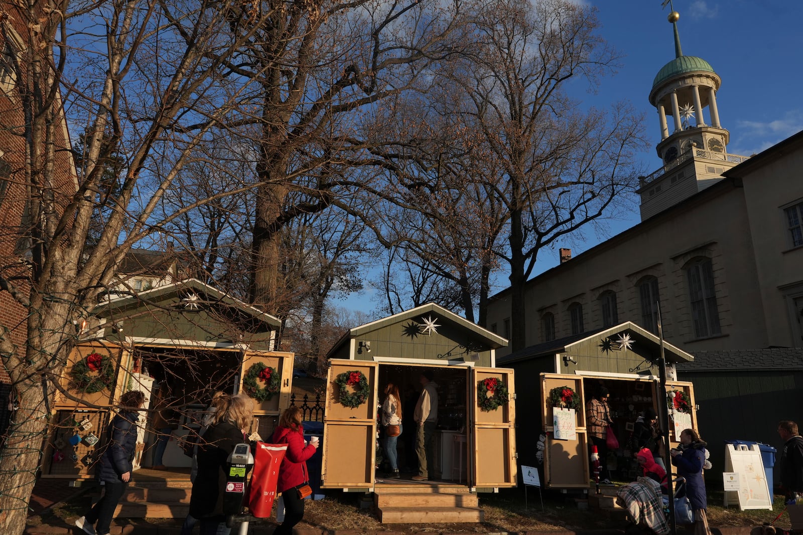 People shop at Christmas-themed wooden huts located next to the Central Moravian Church in Bethlehem, Pa., on Sunday, Dec. 1, 2024. (AP Photo/Luis Andres Henao)