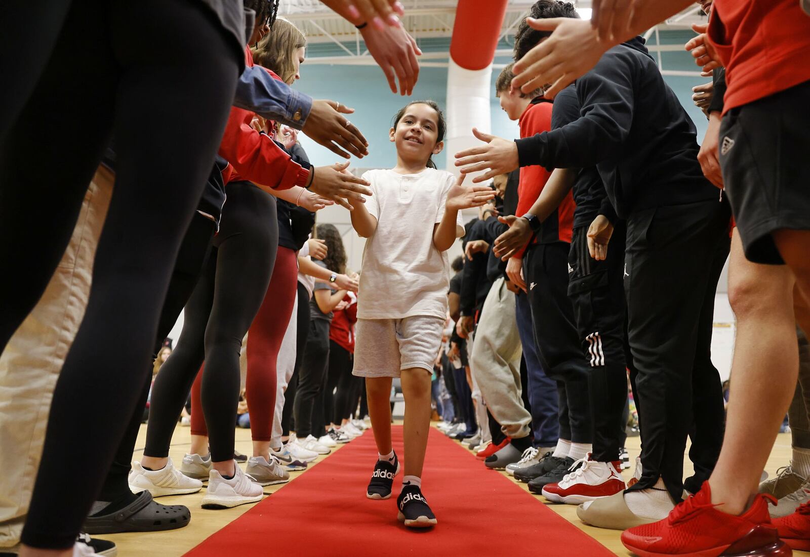 Sebastion Galan walks the red carpet between Fairfield senior students to get his new shoes. Fifth-grade students at Fairfield Central Elementary were given new shoes during a surprise assembly Friday, March 15, 2024 thanks to some fundraising and help from an Ohio-based, non-profit organization called Just a Pair of Shoes. The organization is focused on one mission: to put quality name-brand shoes on young students' feet, boost confidence, and create a sense of belonging. Each fifth grader will be outfitted with a pair of Nike shoes. They got the sizes by having the students measure their feet under the guise of a math lesson. NICK GRAHAM/STAFF