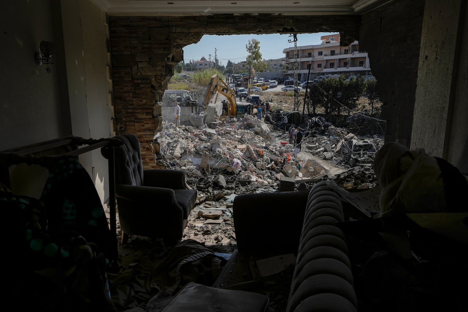 Rescue workers use an excavator to clear the rubble of a destroyed building hit Tuesday night in an Israeli airstrike, as they search for victims, in Sarafand, southern Lebanon, Wednesday, Oct. 30, 2024. (AP Photo/Bilal Hussein)