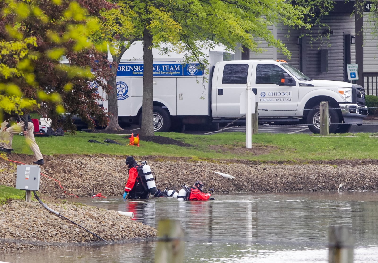 Ohio Bureau of Criminal Investigation forensic dive team searches the pond Tuesday, April 30, 2019 behind an apartment building where four people were found dead early Monday morning at Lakefront at West Chester apartments in West Chester Township. NICK GRAHAM/STAFF