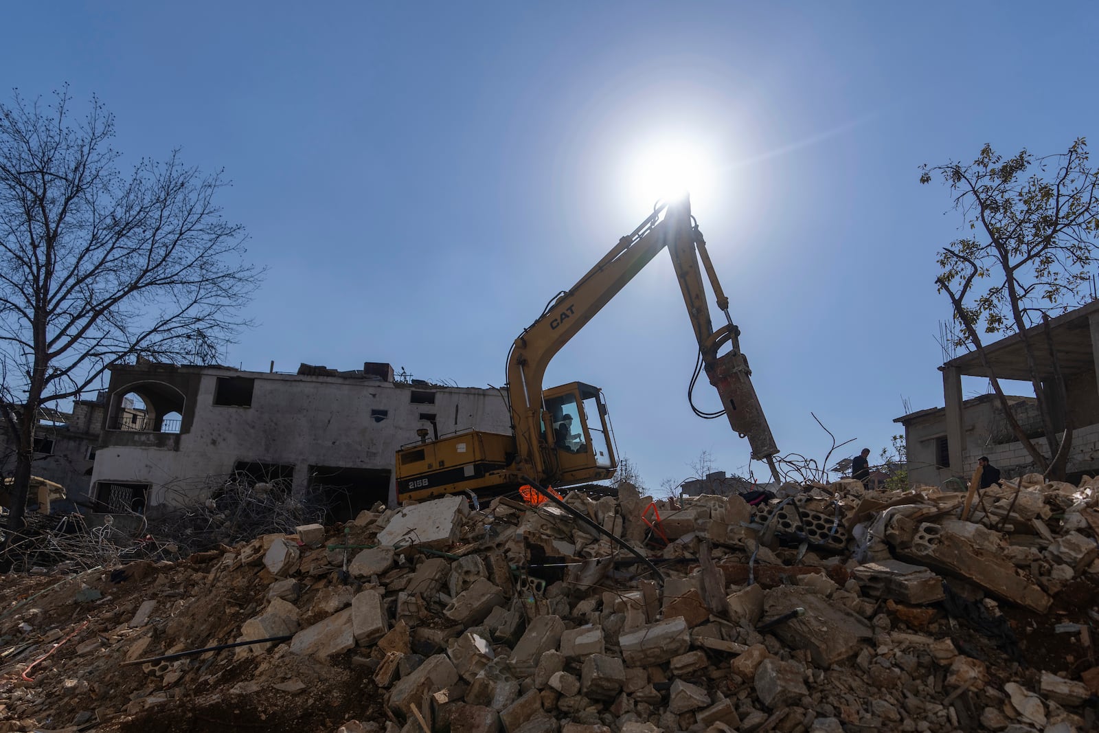 A bulldozer equipped with drill works on the rubble of destroyed houses, caused by the Israeli air and ground offensive, in the town of Khiam, southern Lebanon, Monday, Feb. 17, 2025. (AP Photo/Hassan Ammar)