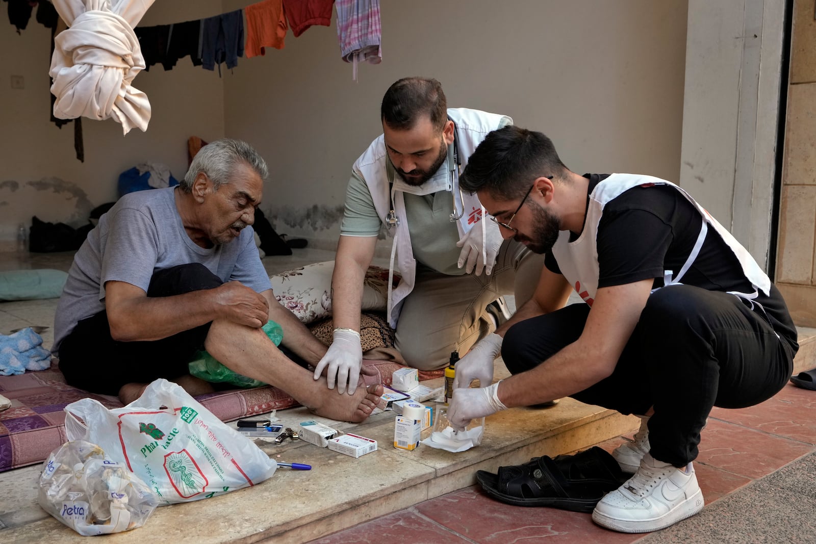 Members of Doctors Without Borders treat a displaced man fleeing the Israeli airstrikes in Dahiyeh, in an empty building complex, in Beirut, Lebanon, Wednesday, Oct. 9, 2024. (AP Photo/Bilal Hussein)