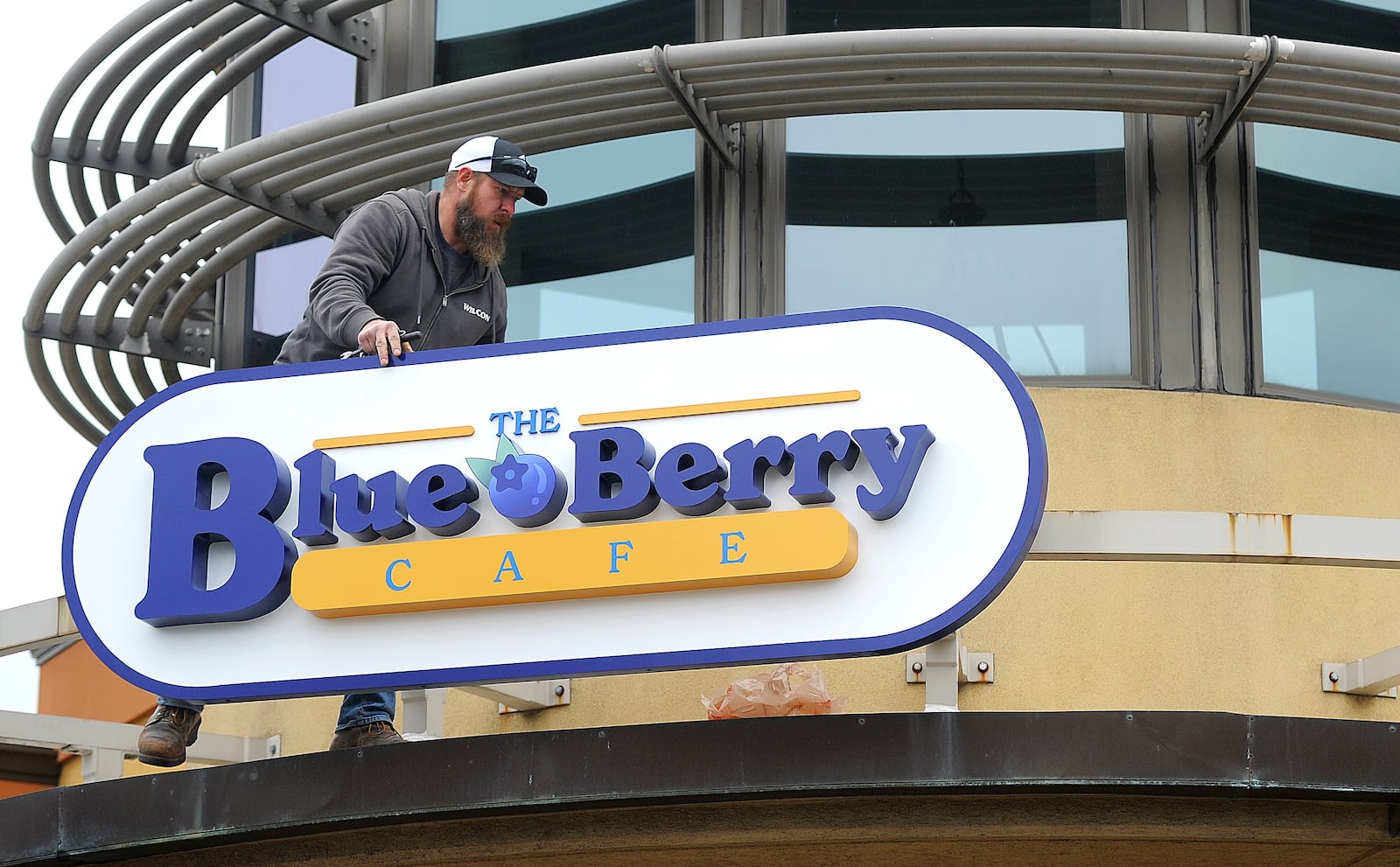 Marc Robinson of Wilcon Construction places The Blue Berry Cafe sign on the old Golden Nuggent Pancake House in Kettering Wednesday, Jan. 3, 2024. MARSHALL GORBY\STAFF