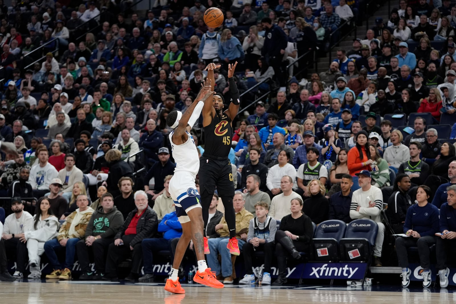 Cleveland Cavaliers guard Donovan Mitchell (45) shoots over Minnesota Timberwolves forward Jaden McDaniels, center left, during the first half of an NBA basketball game, Saturday, Jan. 18, 2025, in Minneapolis. (AP Photo/Abbie Parr)