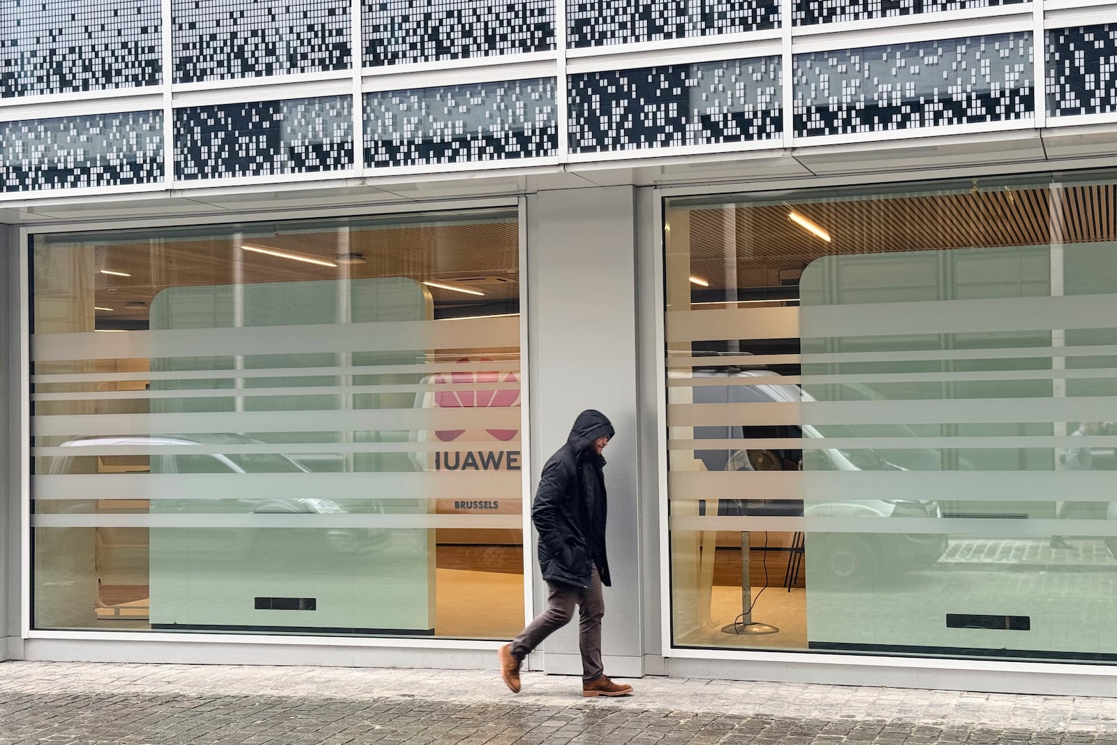 A man walks by the headquarters of Huawei in Brussels, Thursday, March 13, 2025. (AP Photo/Sylvain Plazy)