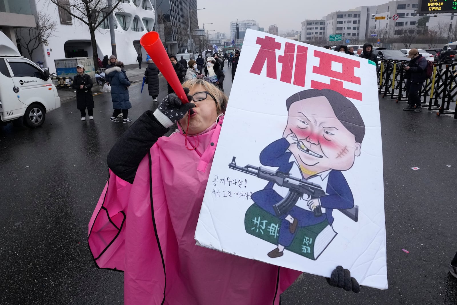 A protester blows a vuvuzela during a rally demanding the arrest of impeached South Korean President Yoon Suk Yeol near the presidential residence in Seoul, South Korea, Monday, Jan. 6, 2025. The letters read "Arrest Yoon Suk Yeol." (AP Photo/Ahn Young-joon)