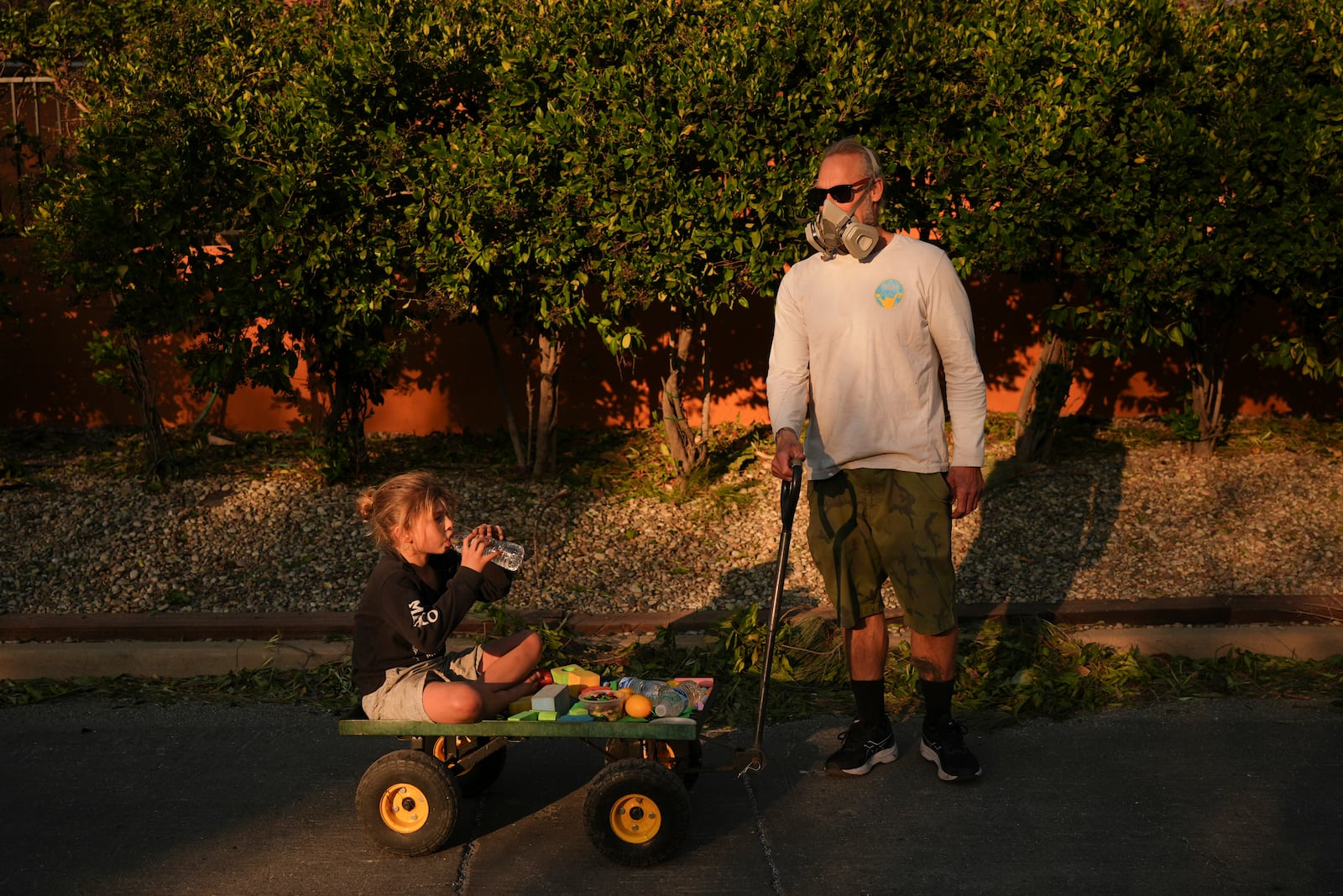 FILE - Resident Pauly Harter, right, pulls his son Gavin on a cart during a walk Friday, Jan. 10, 2025, in Altadena, Calif. (AP Photo/Jae C. Hong, File)