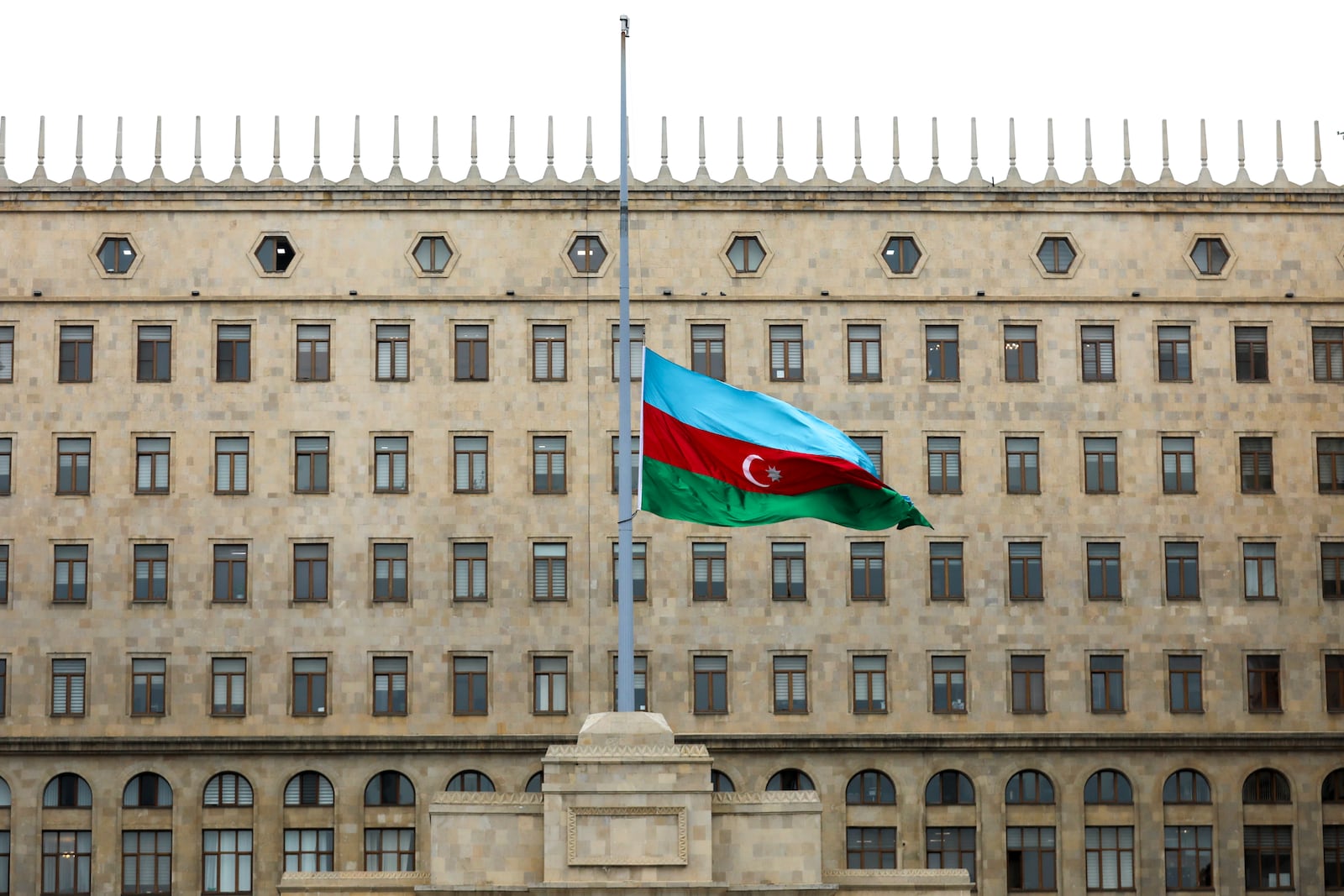 Azerbaijan's national flag at half-mast in the memory of victims of the Azerbaijan Airlines' Embraer 190 that crashed near the Kazakhstan's airport of Aktau, is seen in front of a Government's building in the center of Baku, Azerbaijan, Thursday, Dec. 26, 2024. (AP Photo/Aziz Karimov)