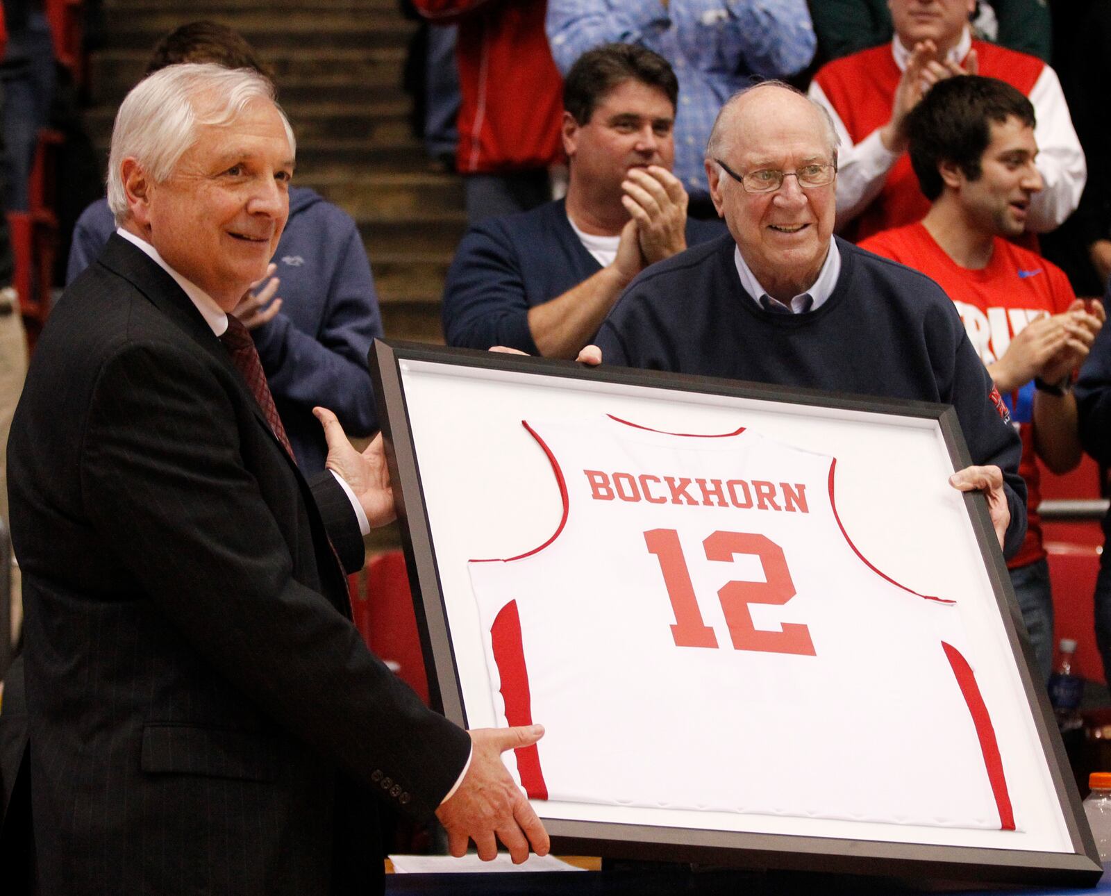 Dayton Athletic Director Tim Wabler, left, presents WHIO's Bucky Bockhorn with a framed jersey during a game against George Mason on Wednesday, Feb. 25, 2015, at UD Arena. David Jablonski/Staff