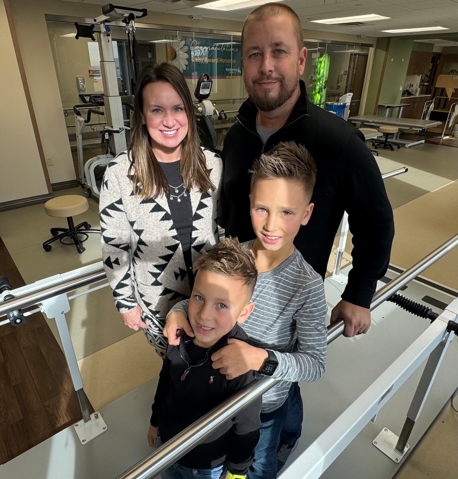 Pictured is Bill Wooley, a former Kettering Health Hamilton patient patient who sustained a severe spinal cord injury after a fall in his home, with his wife, Lauren, and their two children, Beckett and Lincoln. MICHAEL D. PITMAN/STAFF