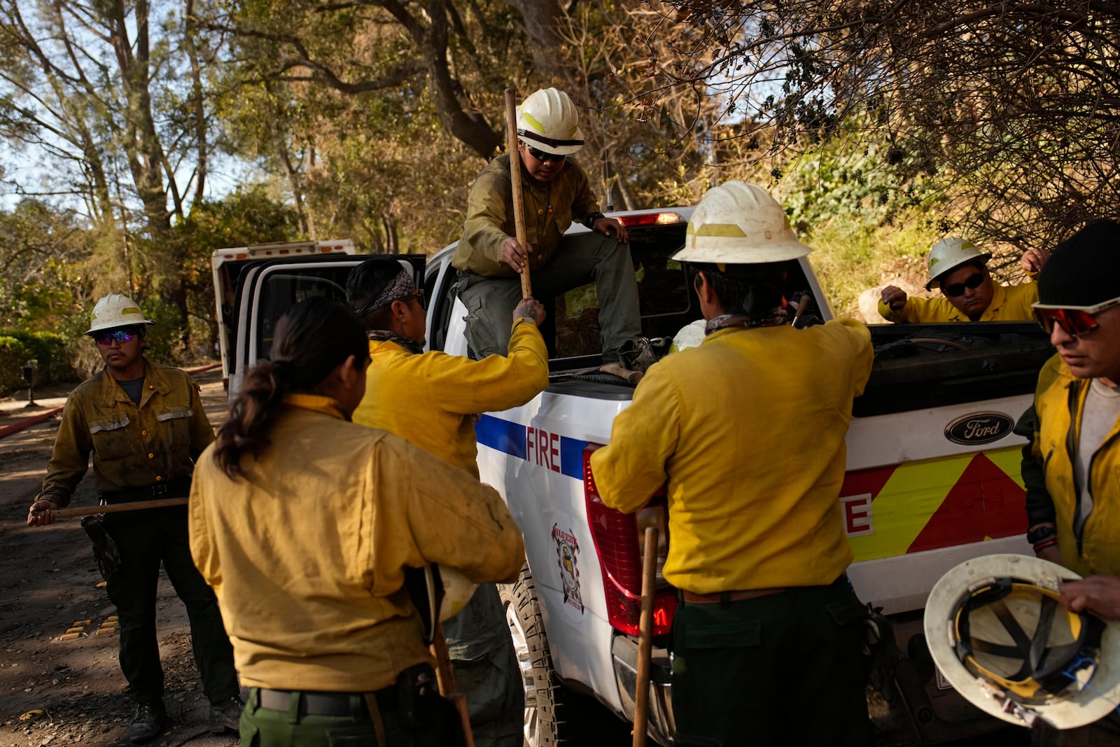 Firefighters from the Navajo Scouts firefighter crew unload hand tools from a truck at the Eaton Fire, Friday, Jan. 17, 2025, in Altadena, Calif. (AP Photo/John Locher)