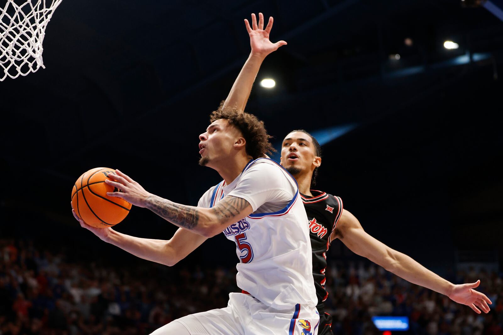 Kansas guard Zeke Mayo (5) goes up to score against Houston guard Milos Uzan, right, during the first half of an NCAA college basketball game, Saturday, Jan. 25, 2025, in Lawrence, Kan. (AP Photo/Colin E. Braley)